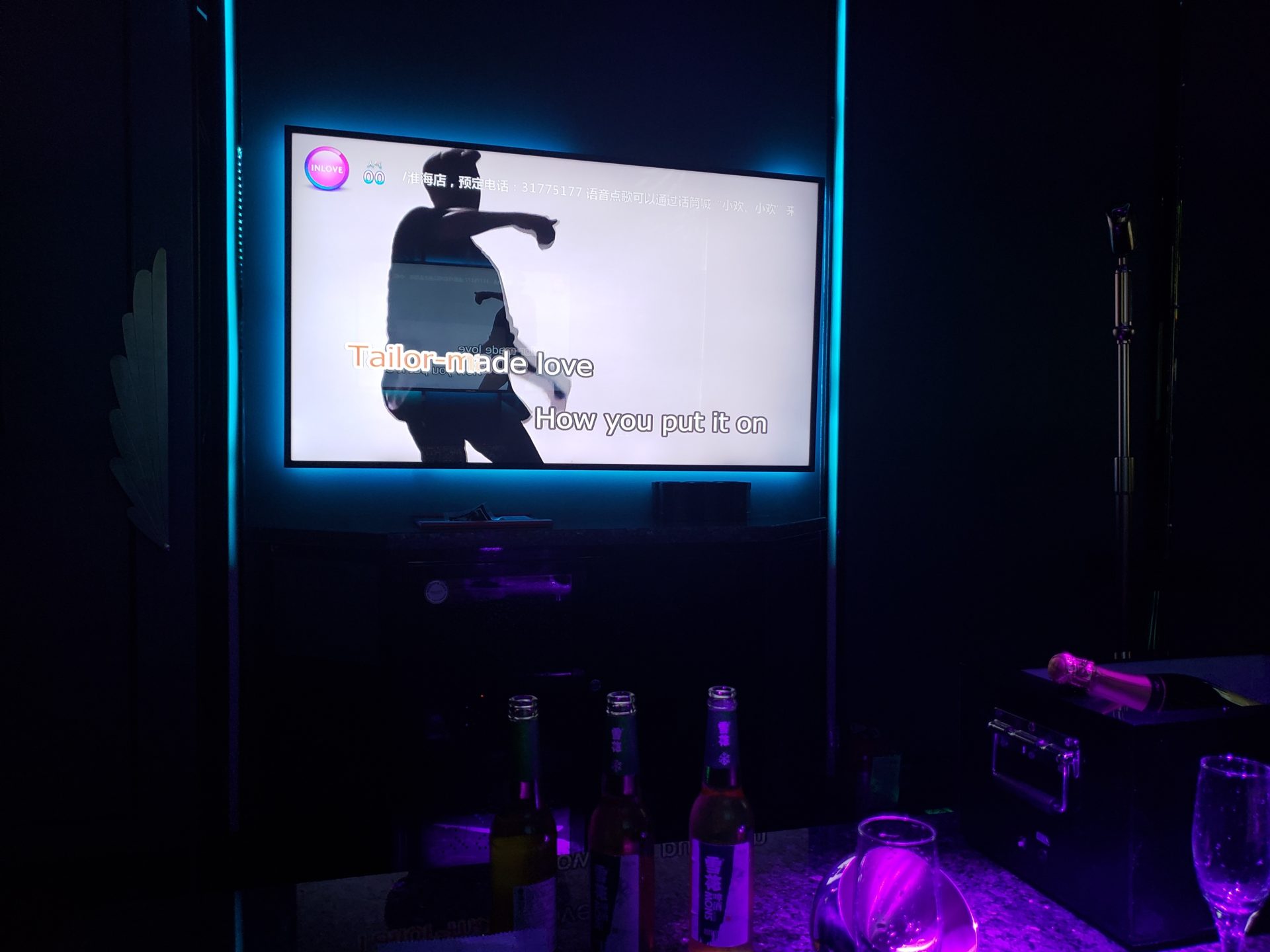 a tv on a wall with a screen and bottles of beer