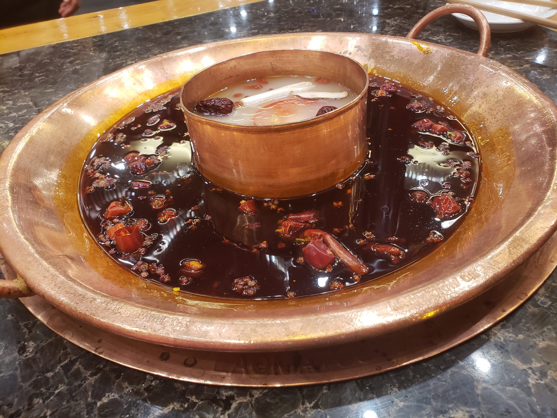 a copper pot with a cup in a bowl of liquid