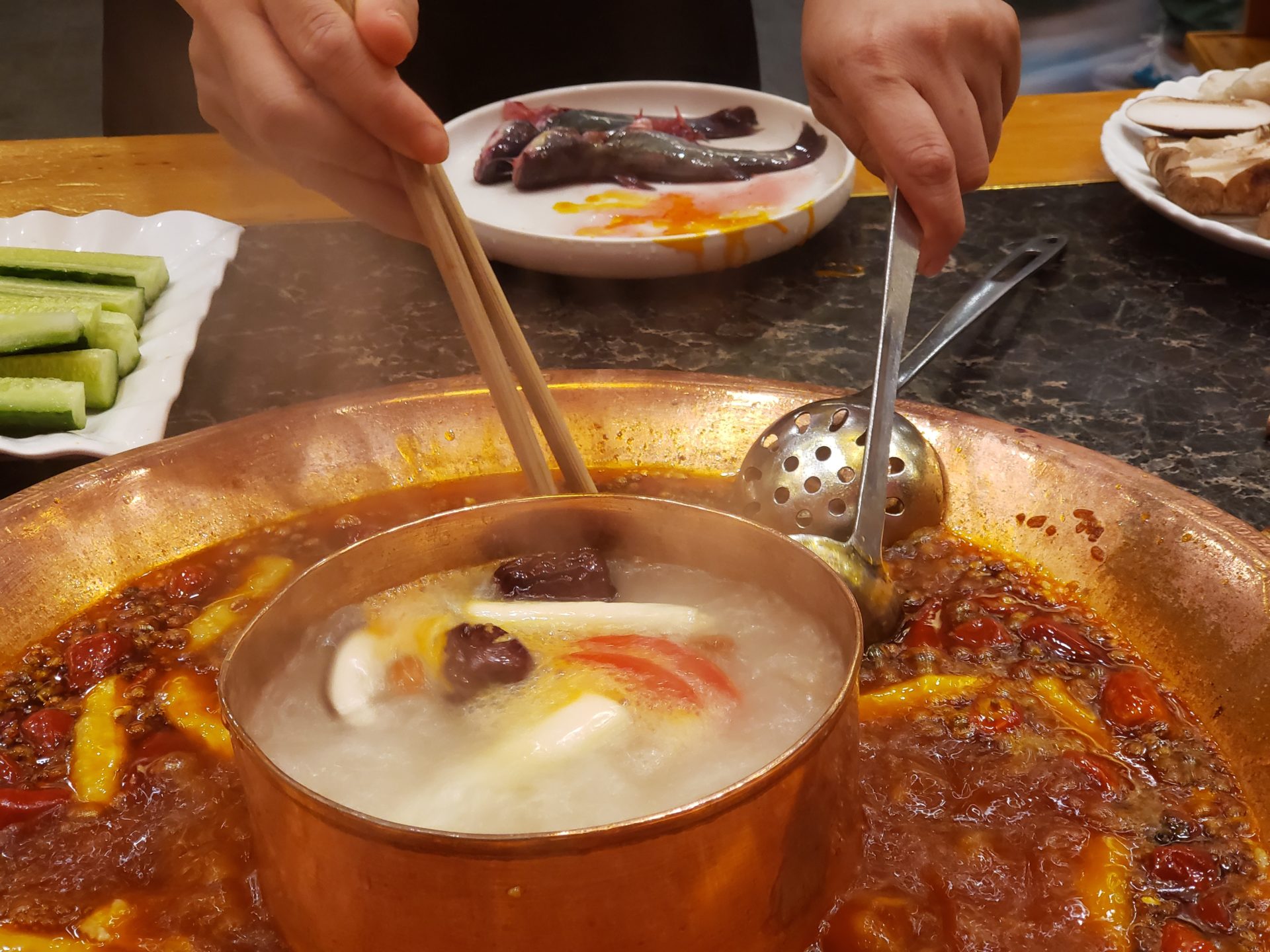 a person holding chopsticks over a pot of soup