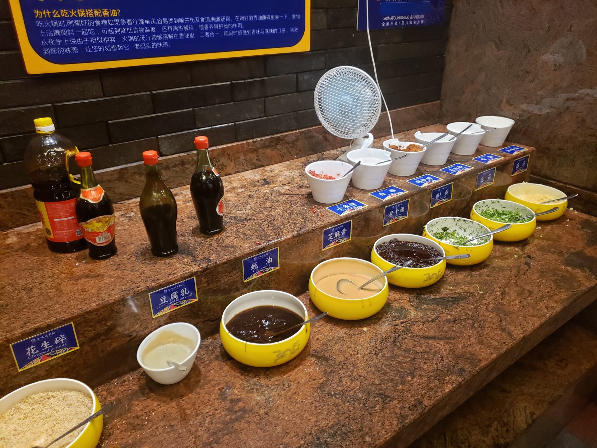 a counter with bowls of food and bottles of sauce