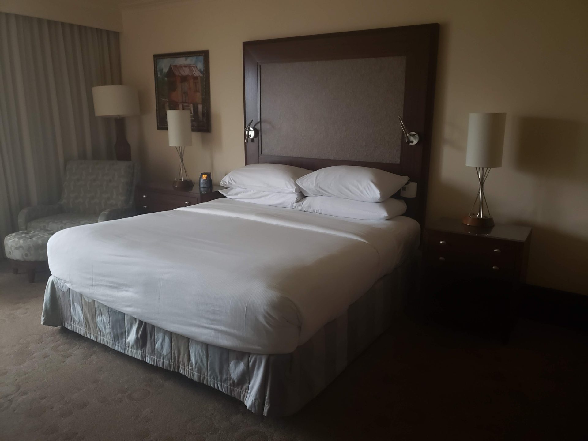 a bed with white sheets and a wood headboard in a hotel room