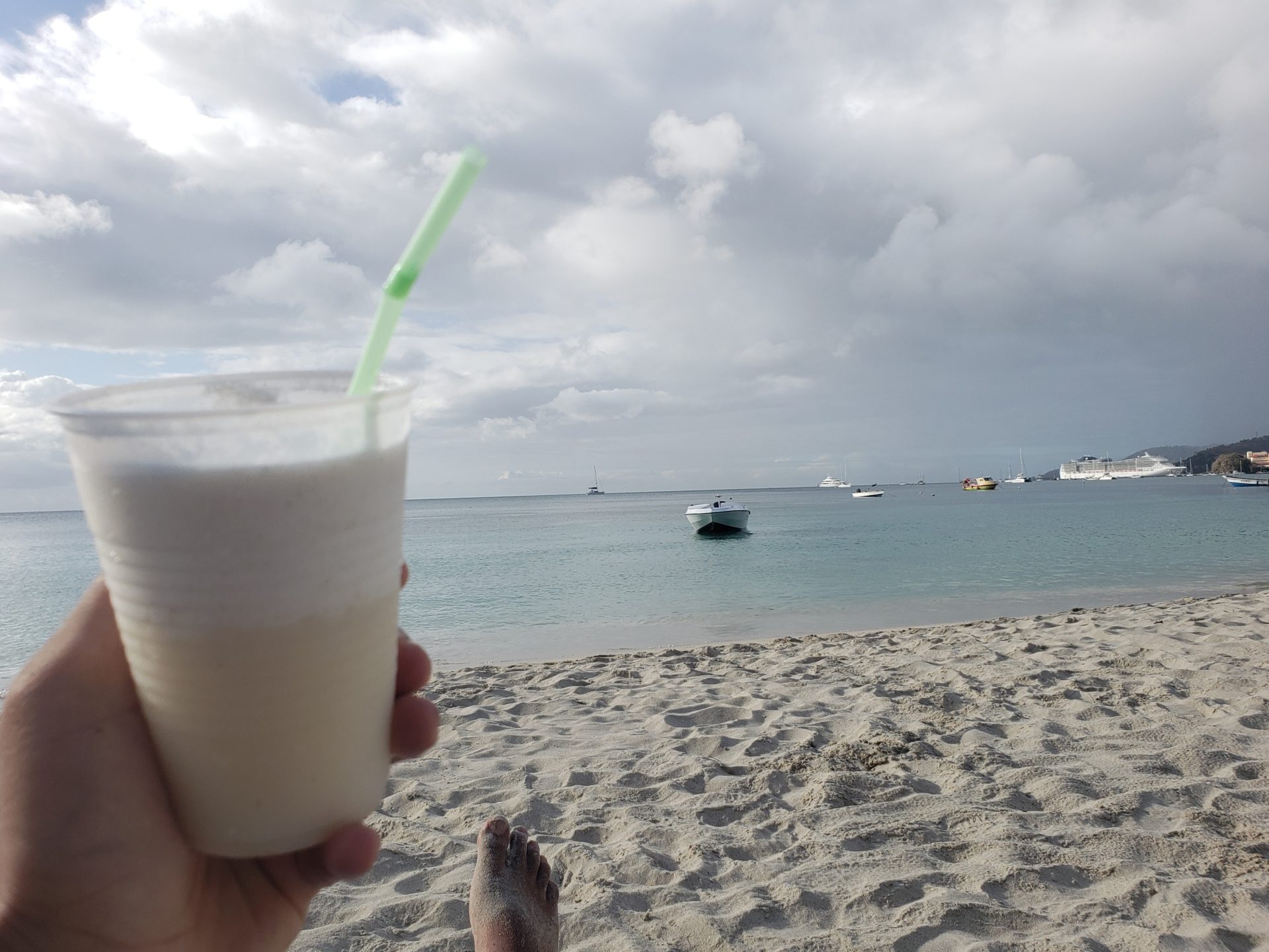 a person holding a cup with a straw on a beach