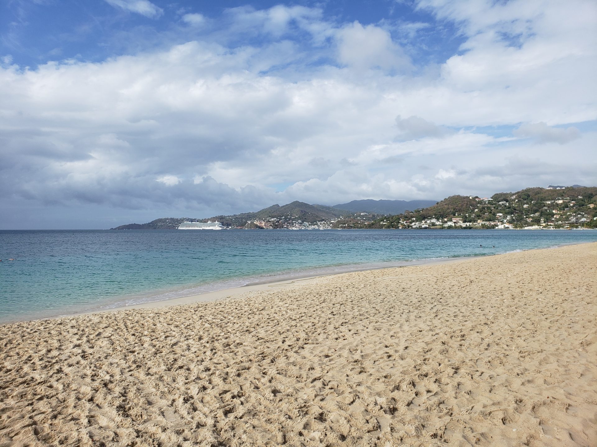 a sandy beach with water and mountains in the background