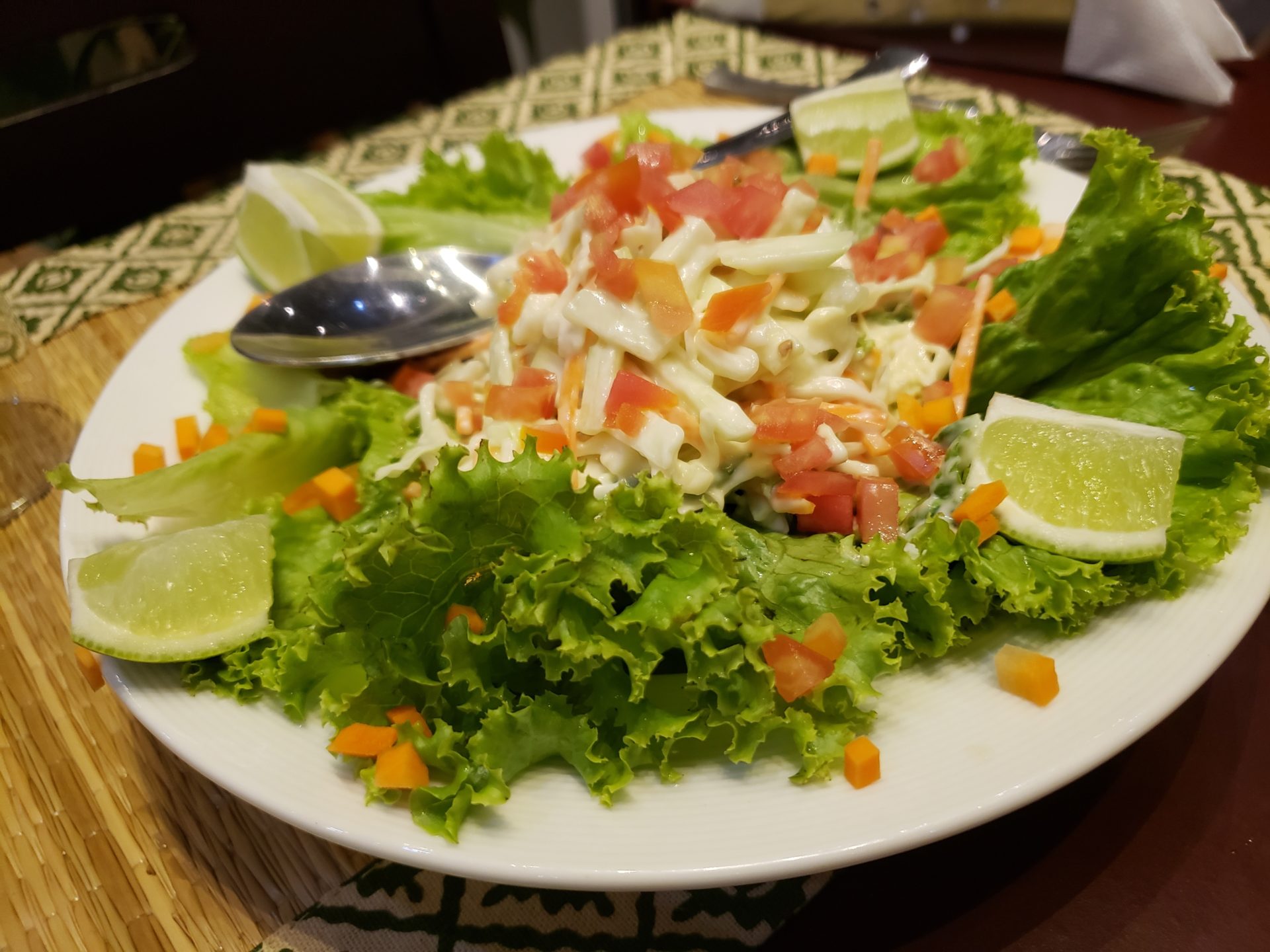 a plate of salad with limes and a spoon