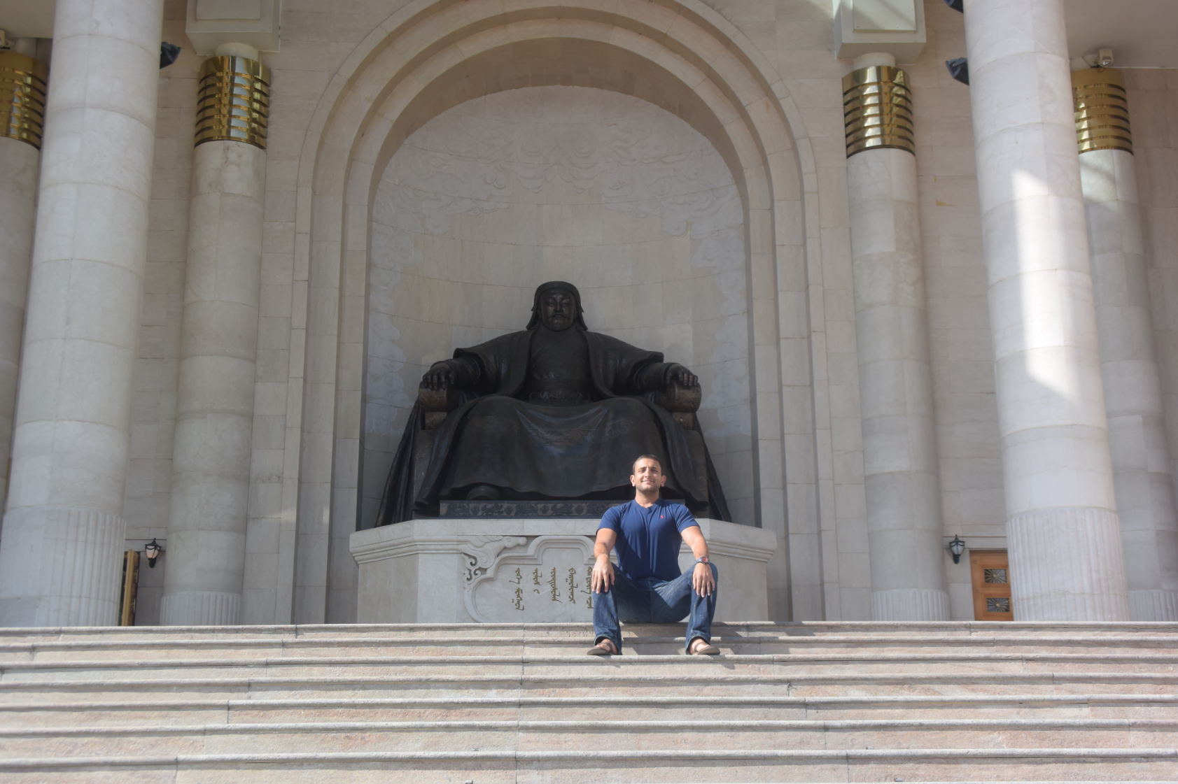 a man sitting on stairs in front of a statue
