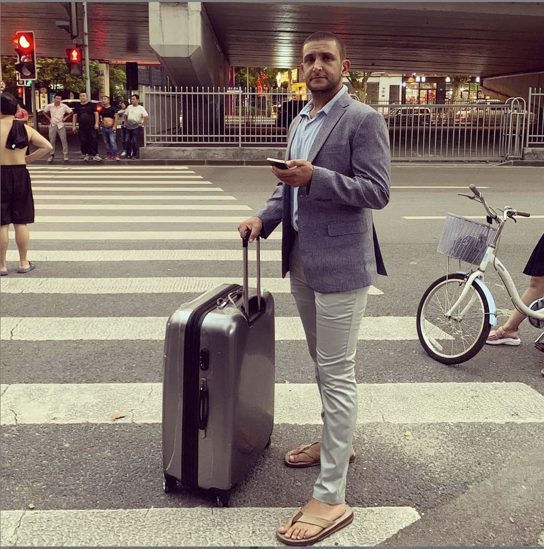 a man standing on a crosswalk holding a suitcase