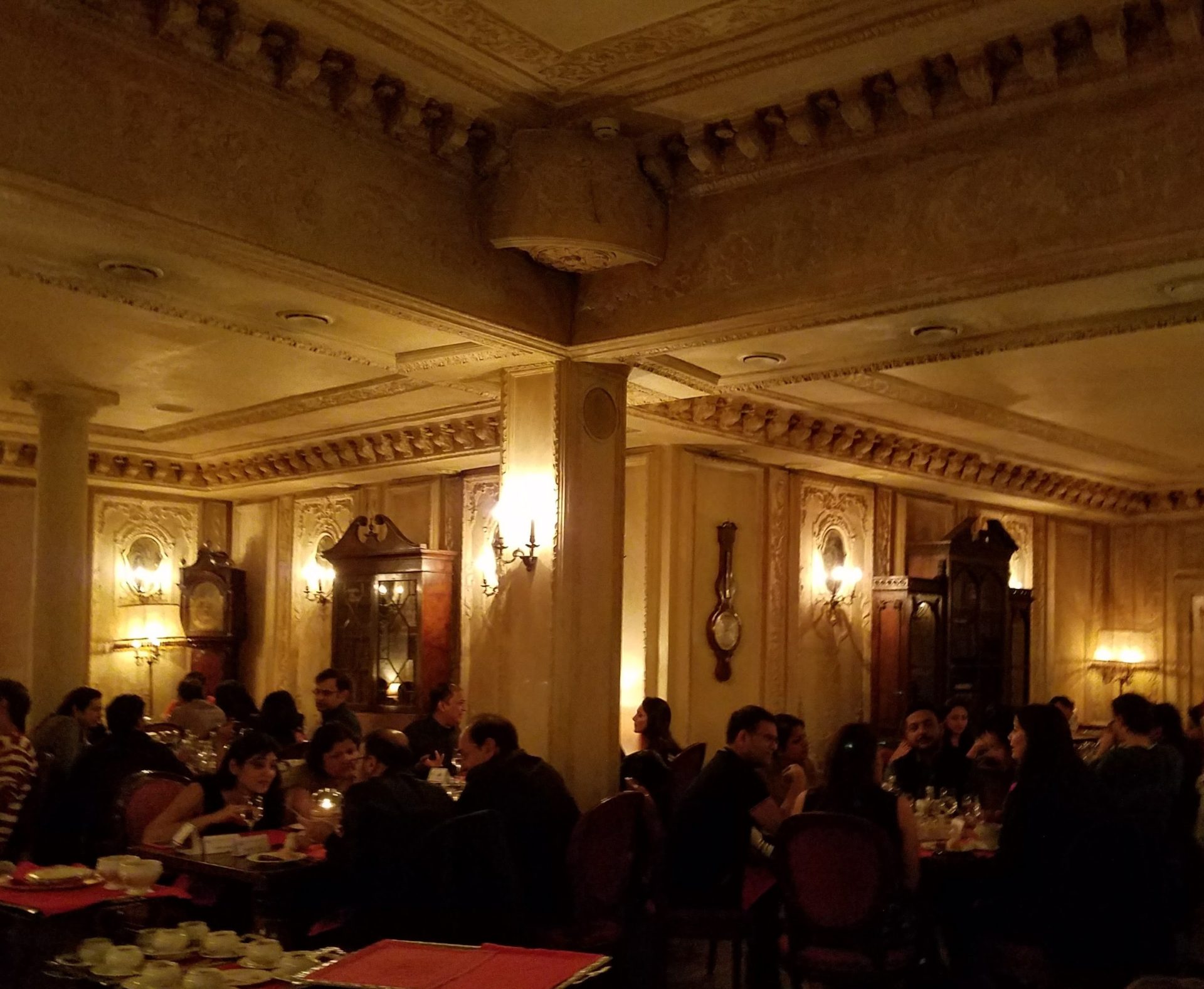 a group of people sitting at tables in a room with ornate ceiling