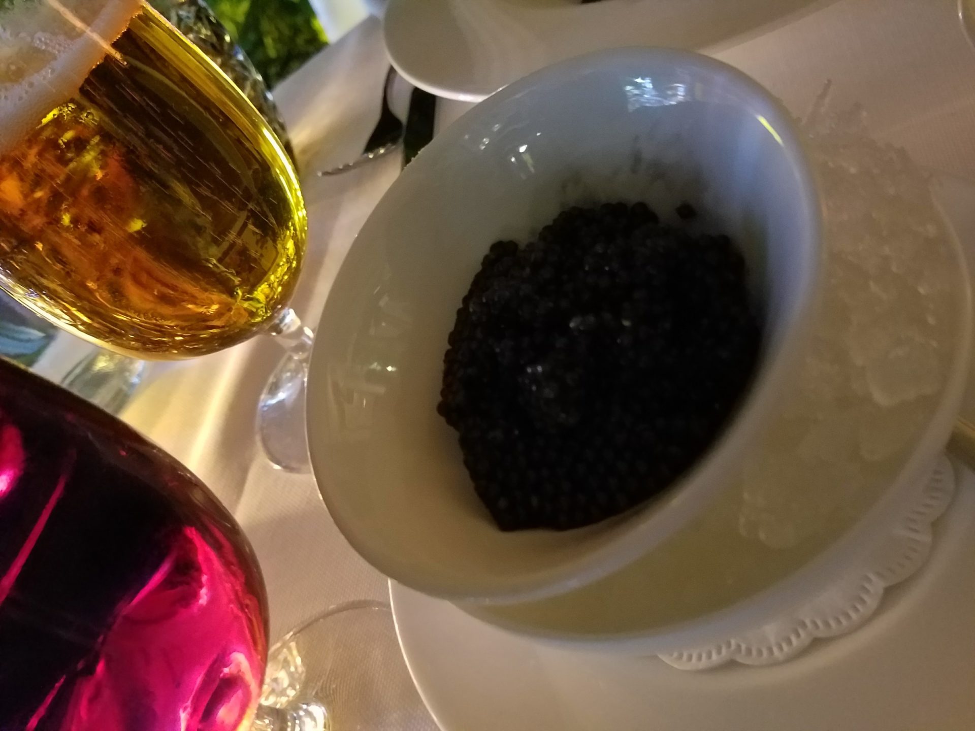 a bowl of black caviar on a white plate
