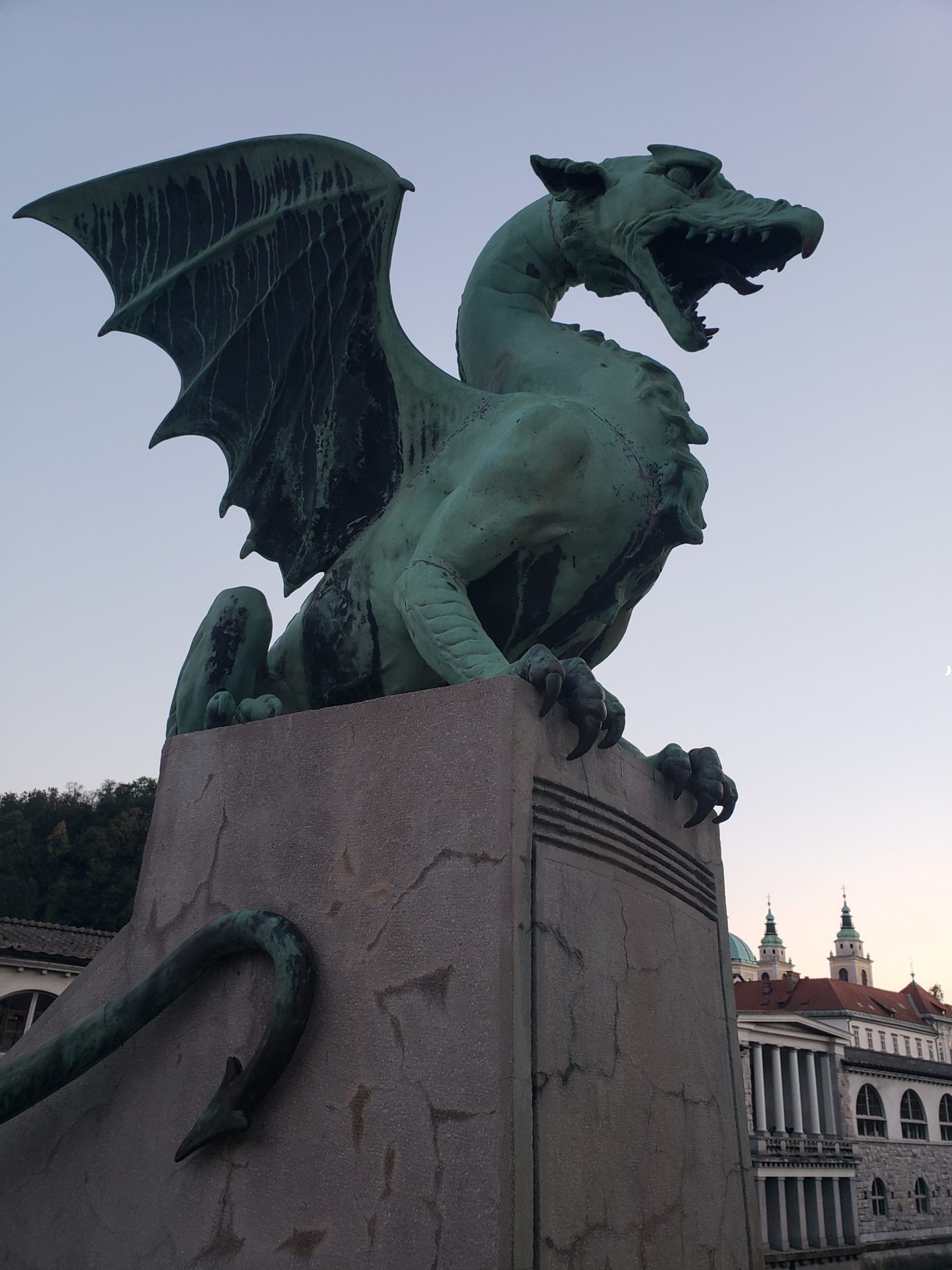 a green dragon statue on a concrete pillar