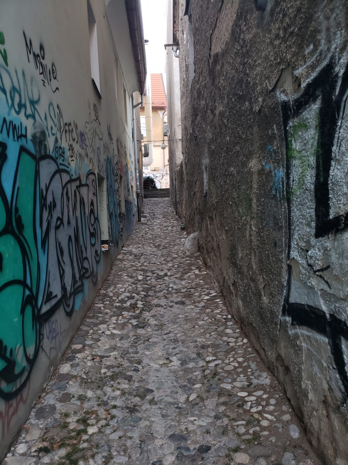 a narrow alleyway with graffiti on the walls