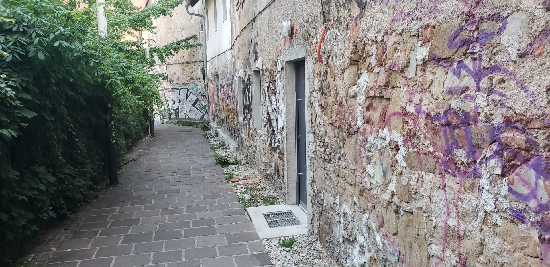 a stone walkway with graffiti on the side of a building