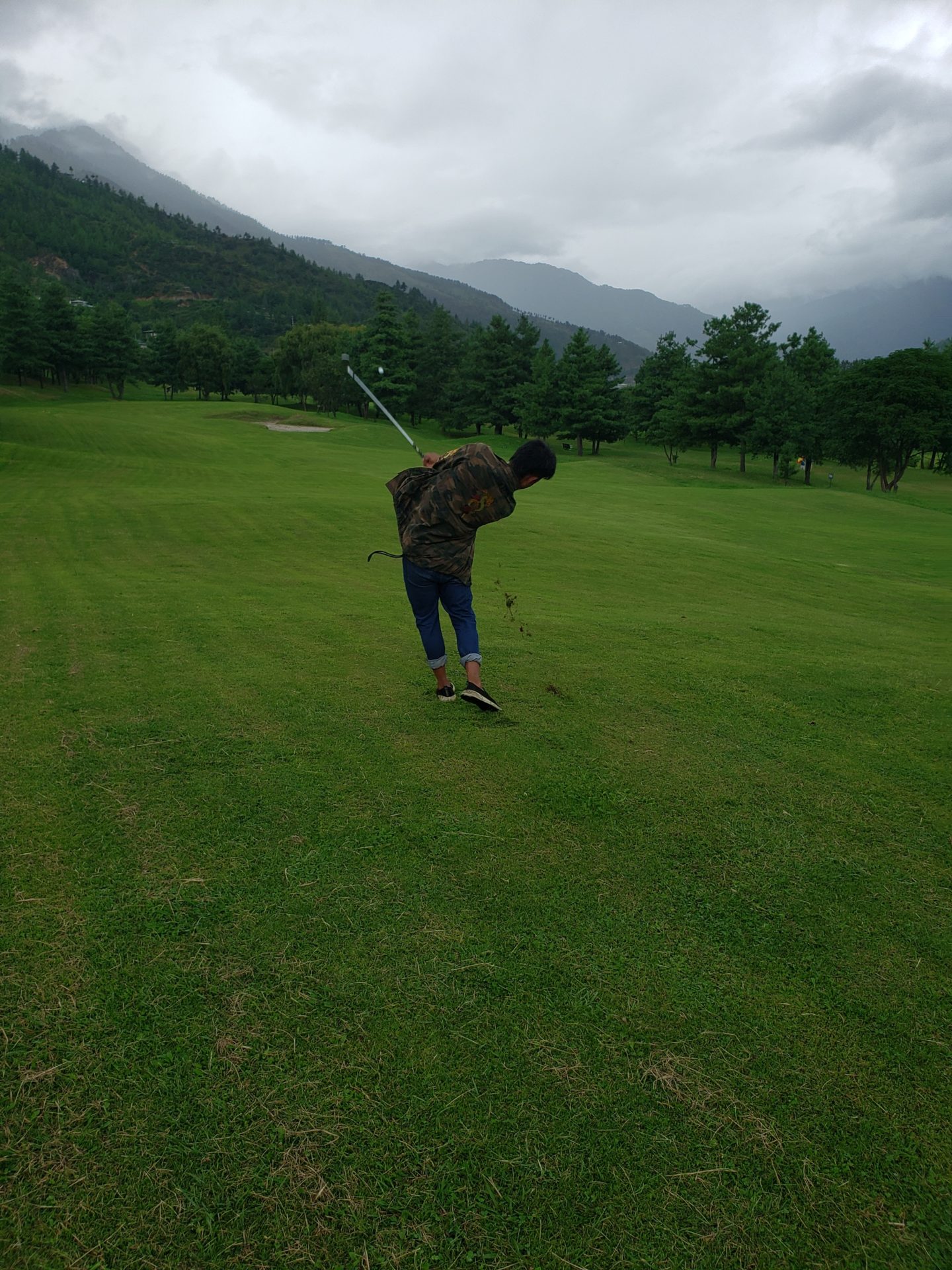 a man holding a golf club in a grassy field