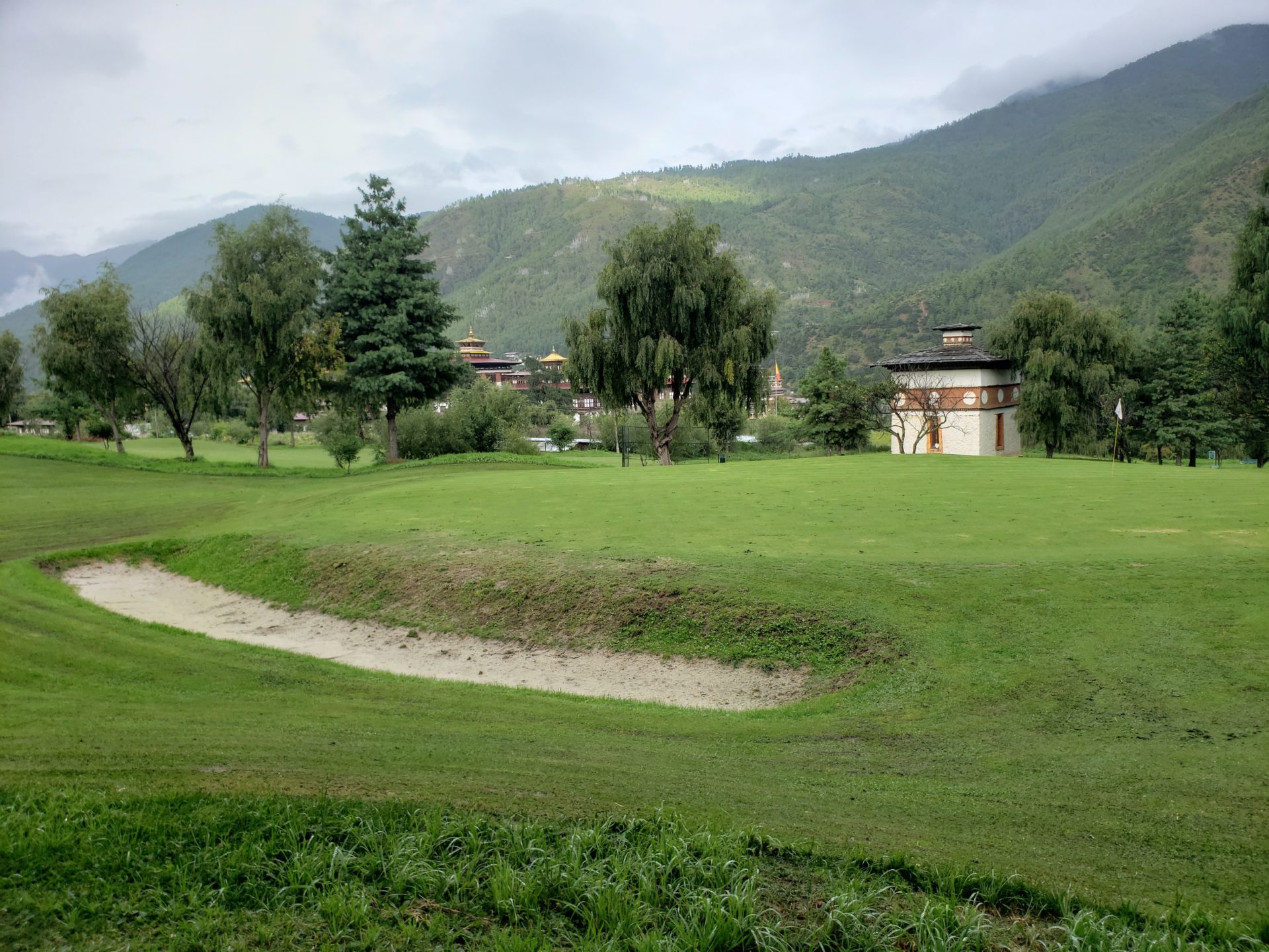 a golf course with a small building and trees