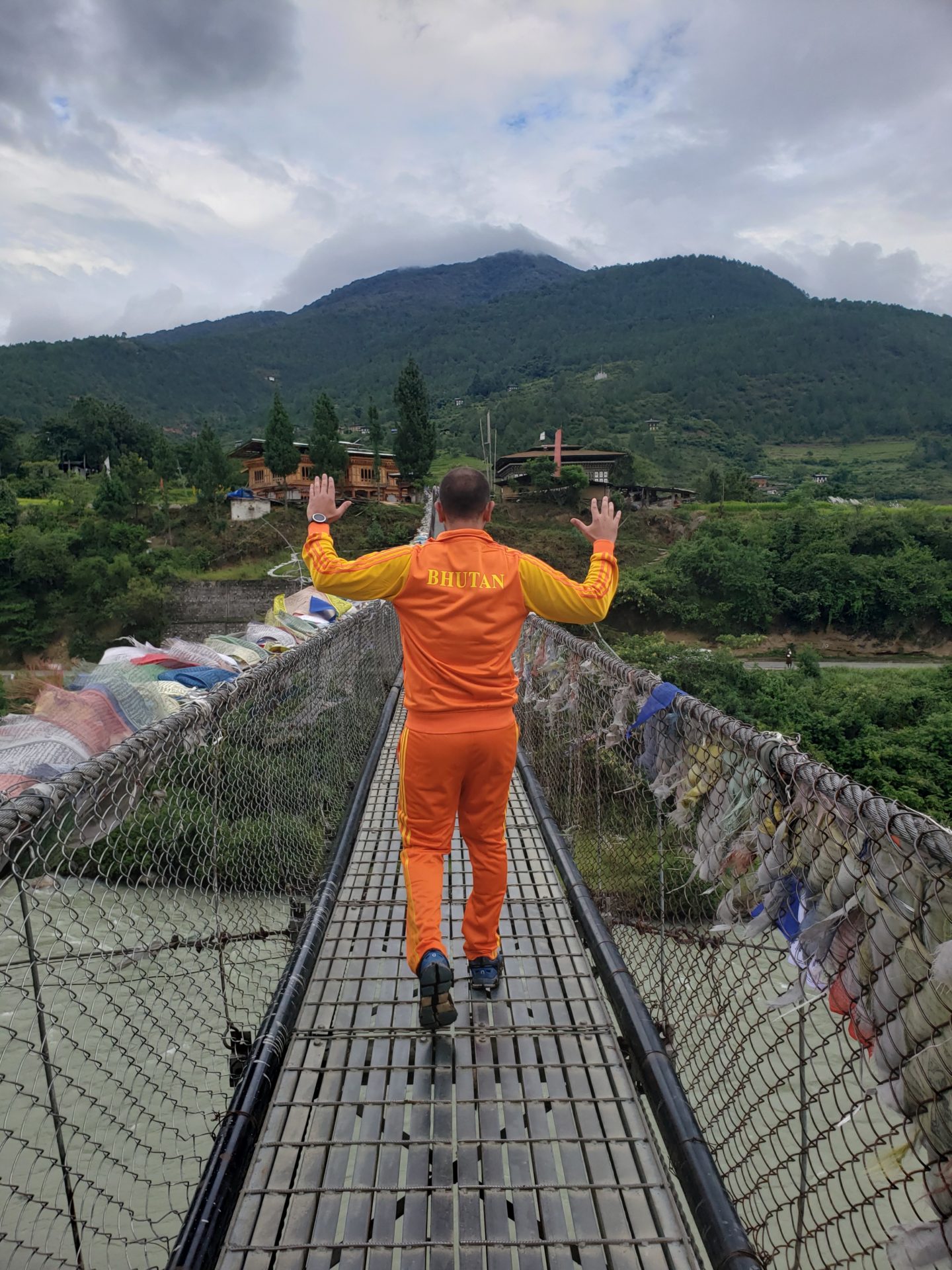 a man in orange jumpsuit standing on a bridge over a river
