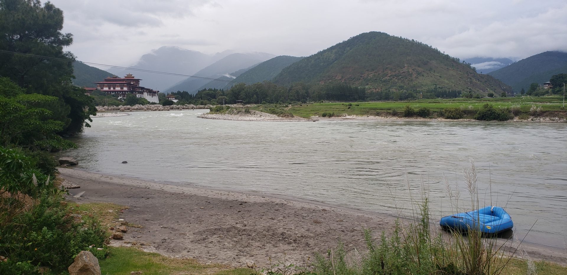 a river with a house and mountains in the background