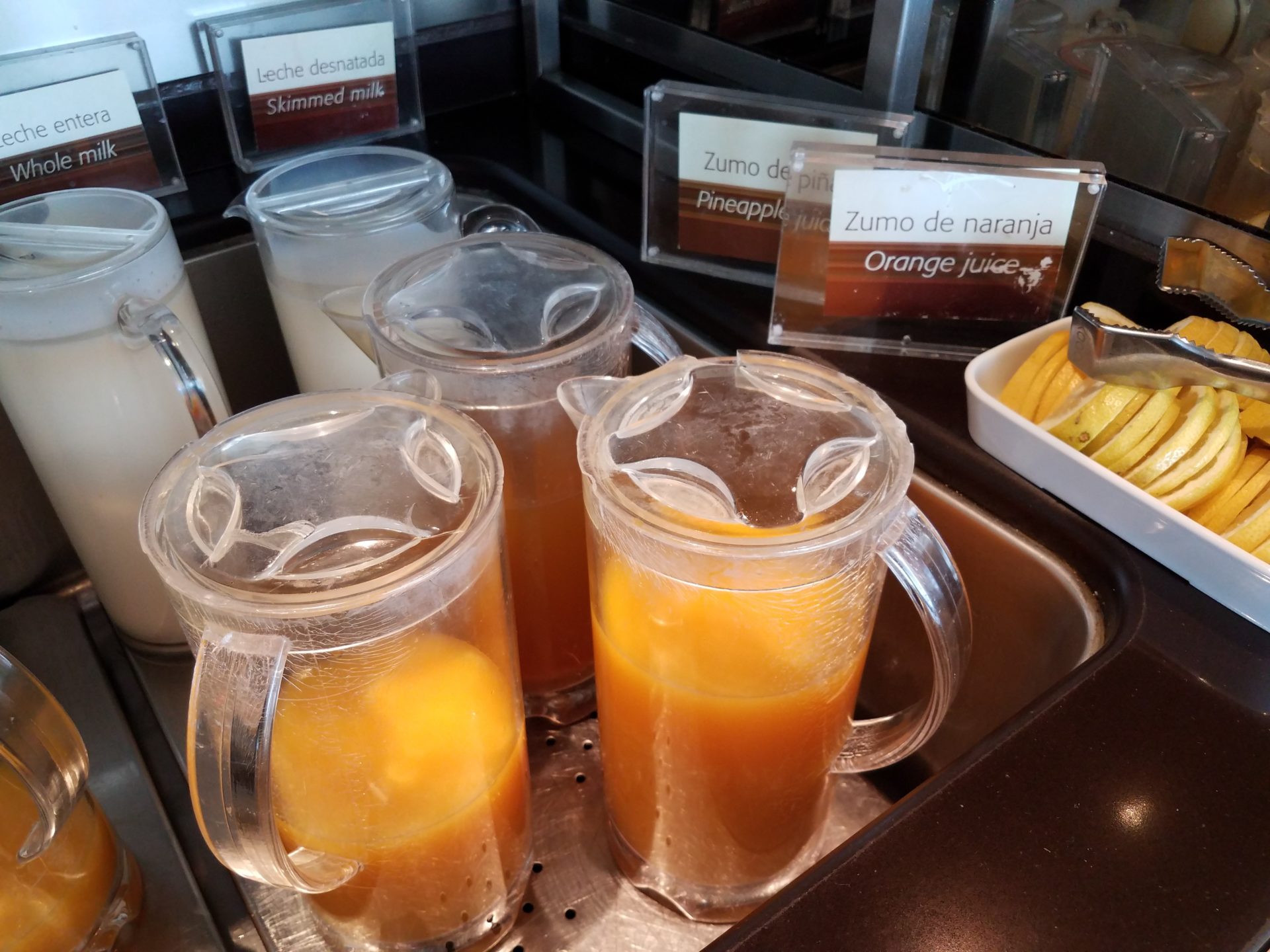 a group of clear jugs with orange juice in them