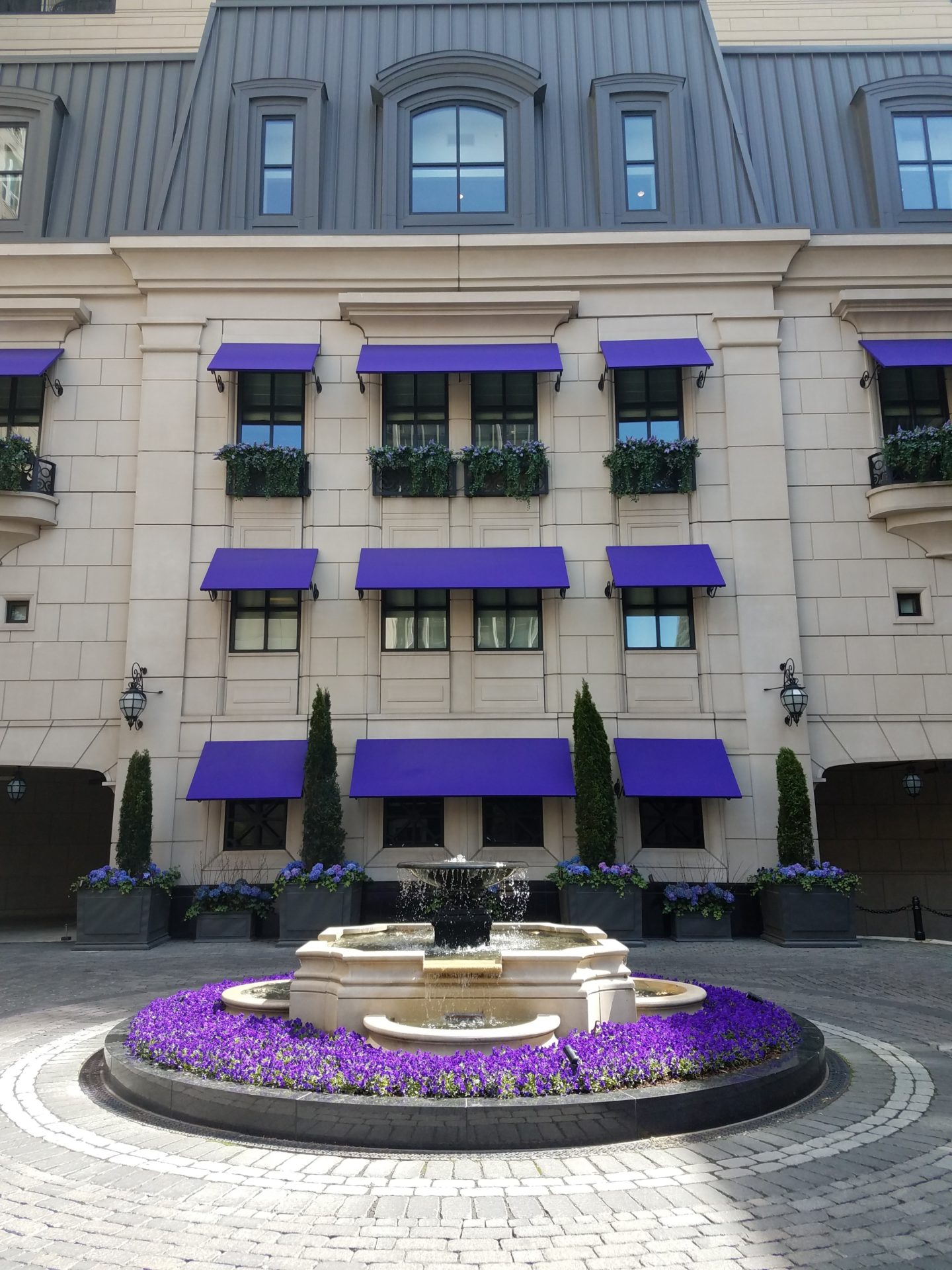 a fountain in front of a building with purple awnings
