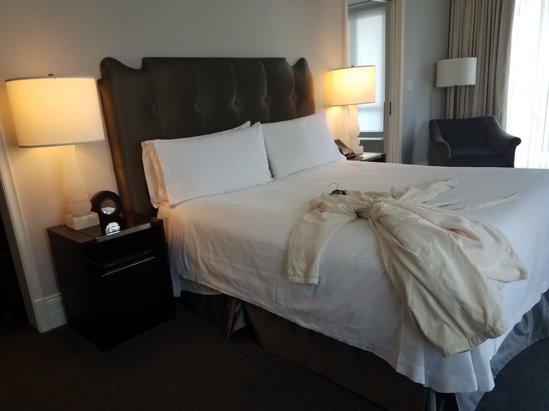 a bed with white sheets and a robe on it