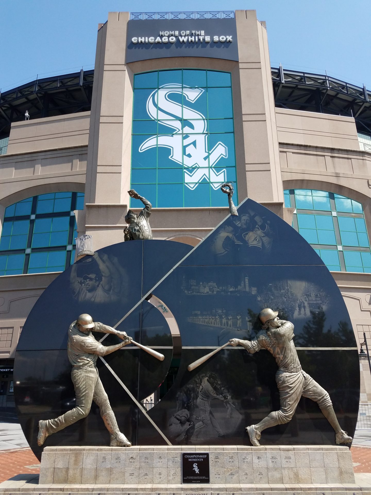 a statue of baseball players in front of a stadium