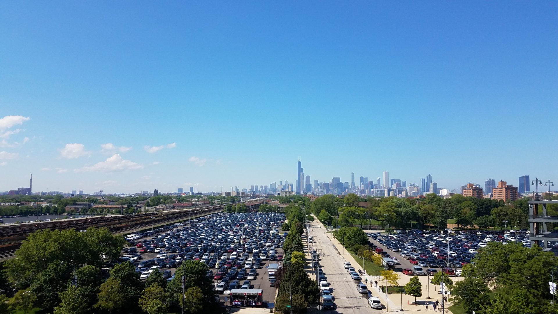 a parking lot with cars and trees and a city in the background
