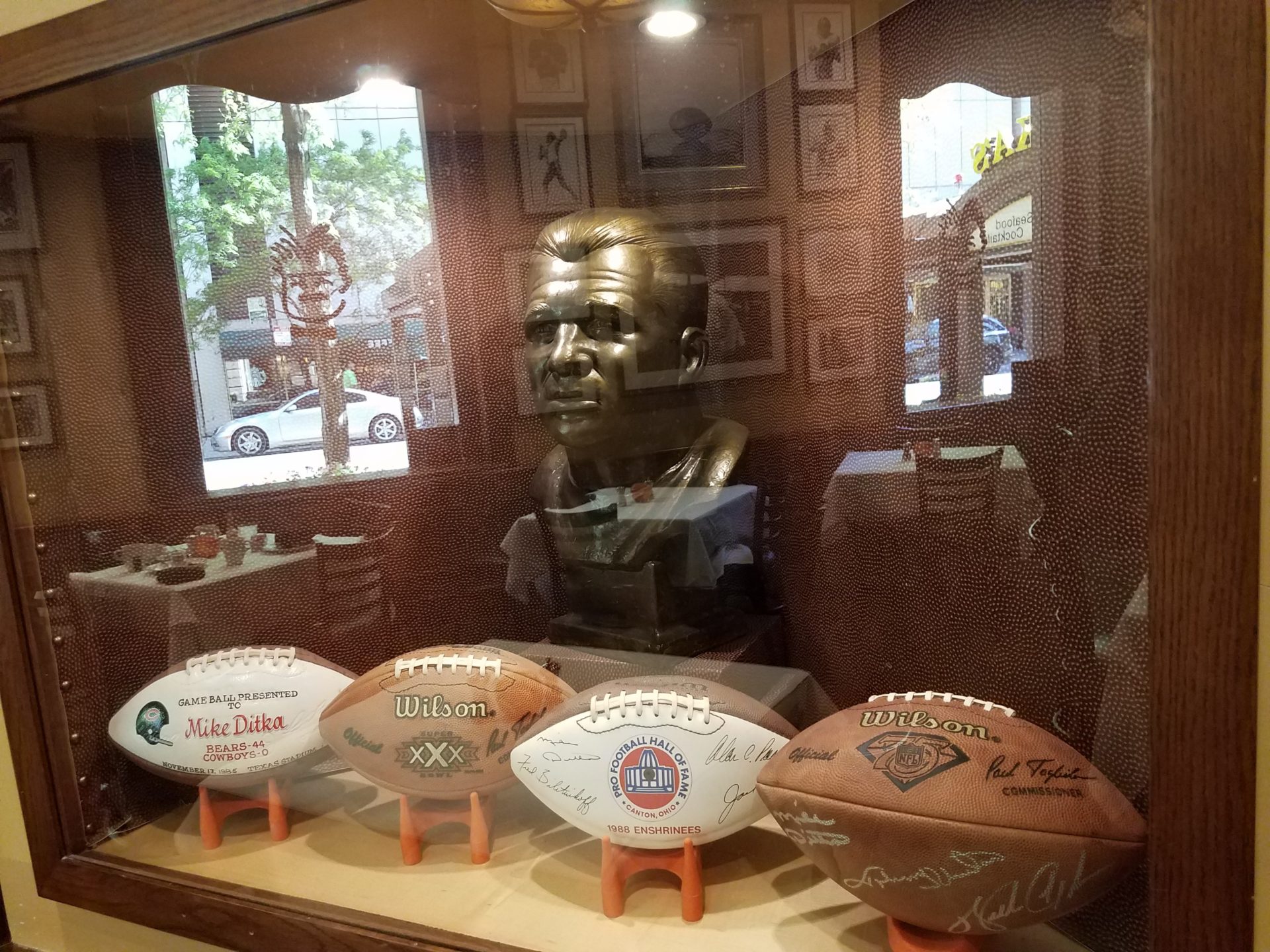 a statue of a man with footballs in a glass case