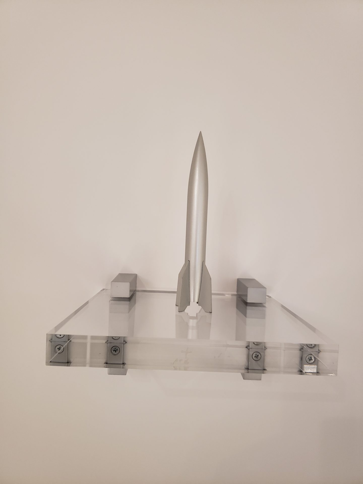 a silver rocket on a clear shelf