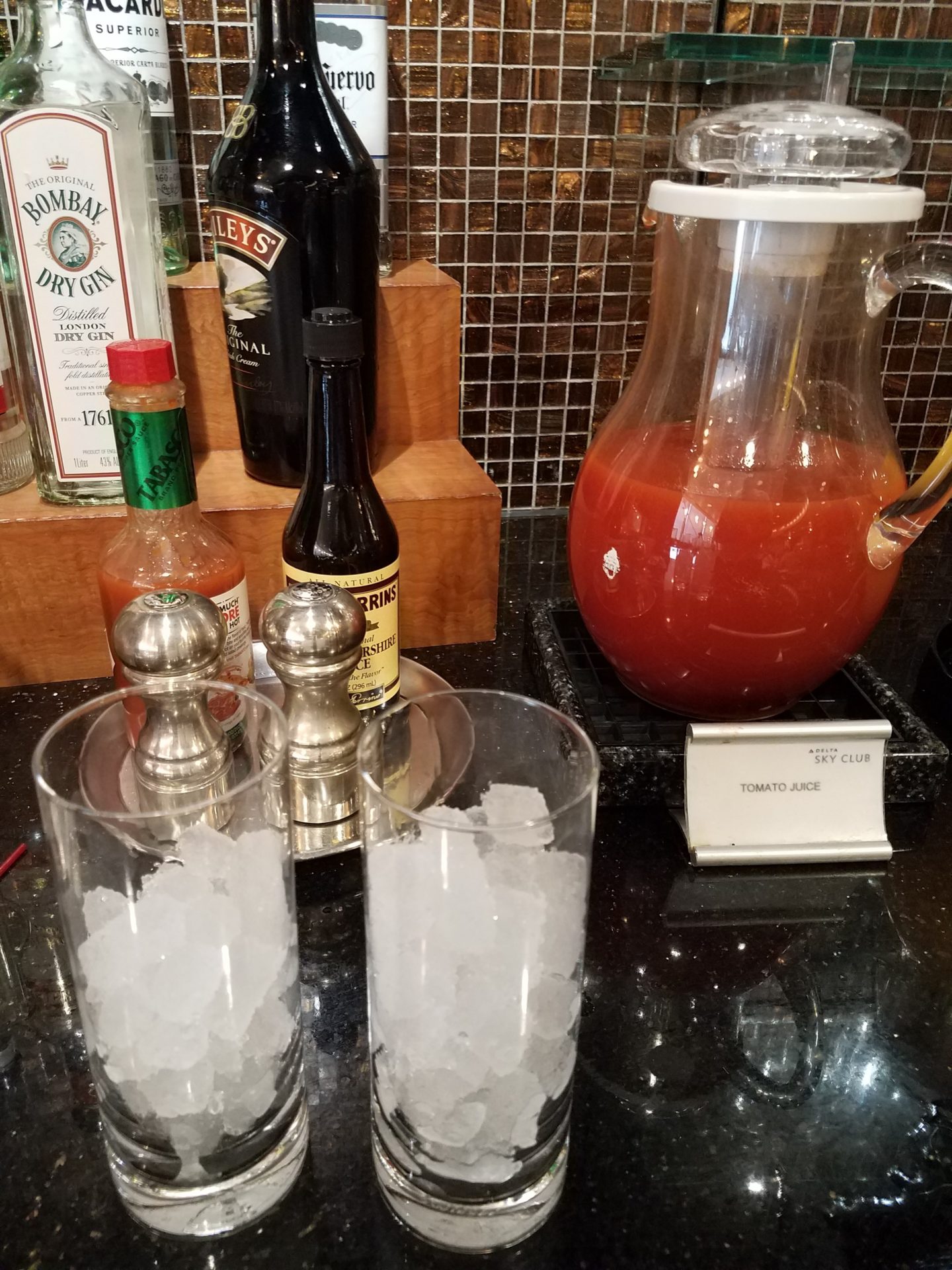 a glass pitcher and glasses with ice on a counter