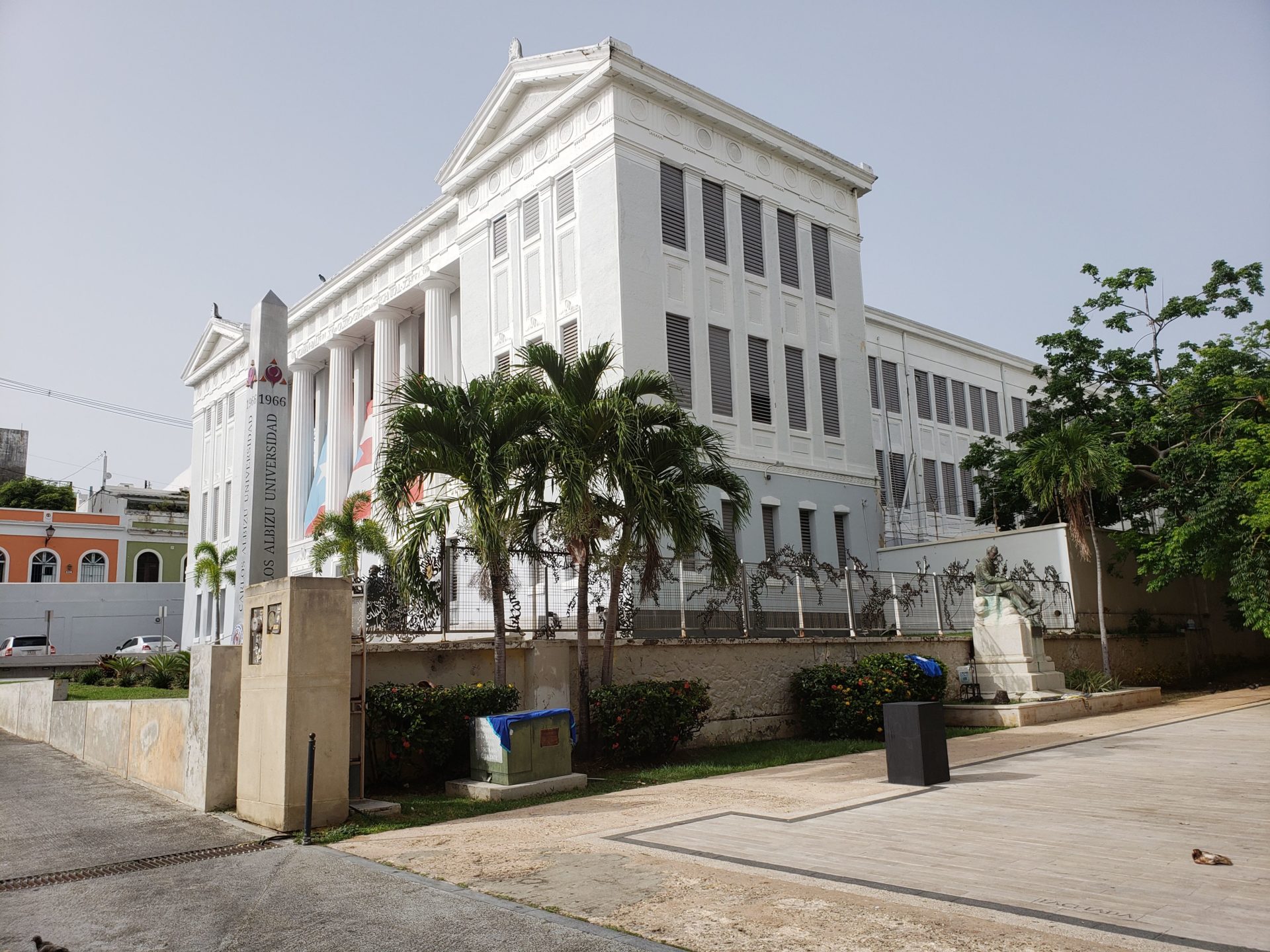 a white building with columns and palm trees