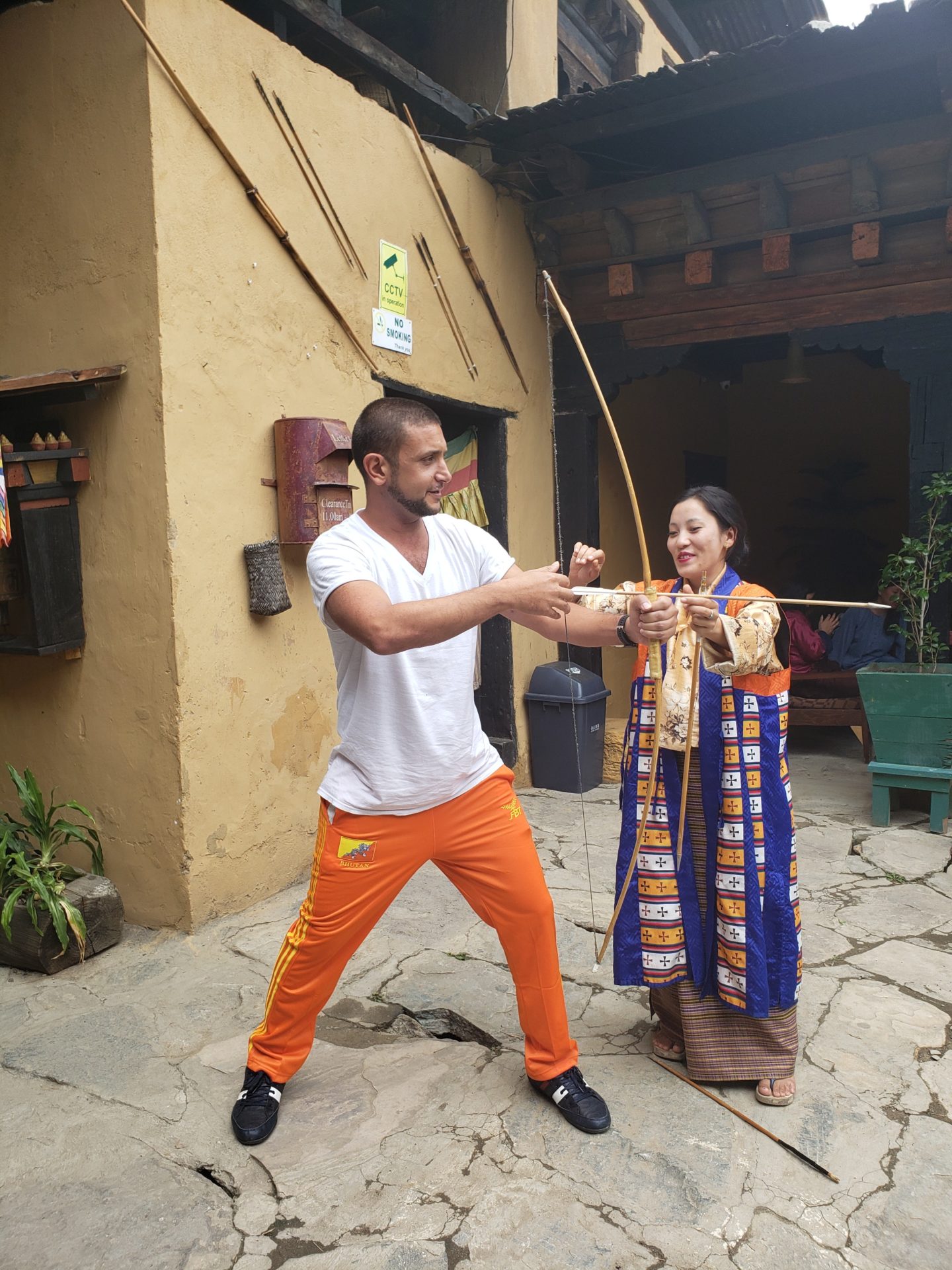 a man and woman shooting a wooden bow and arrow