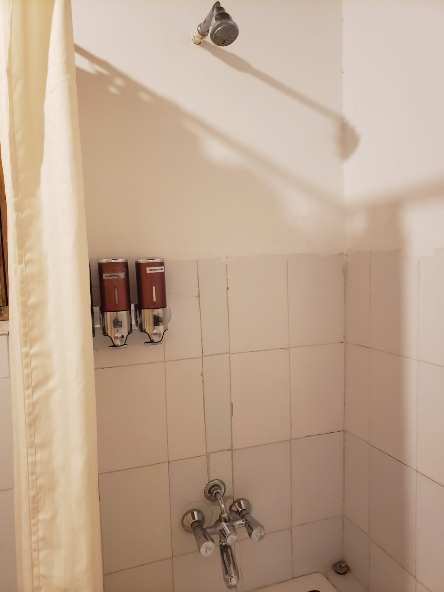 a shower curtain and soap dispensers on a wall