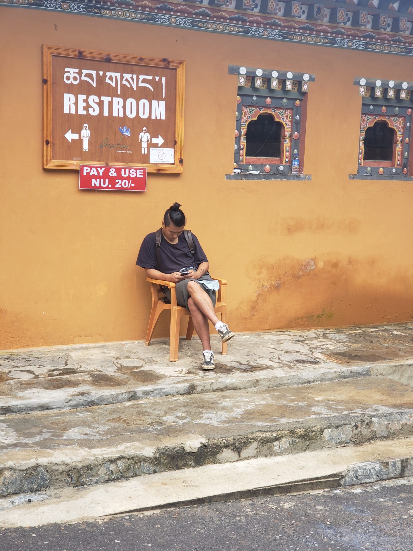 a man sitting on a chair outside a restroom