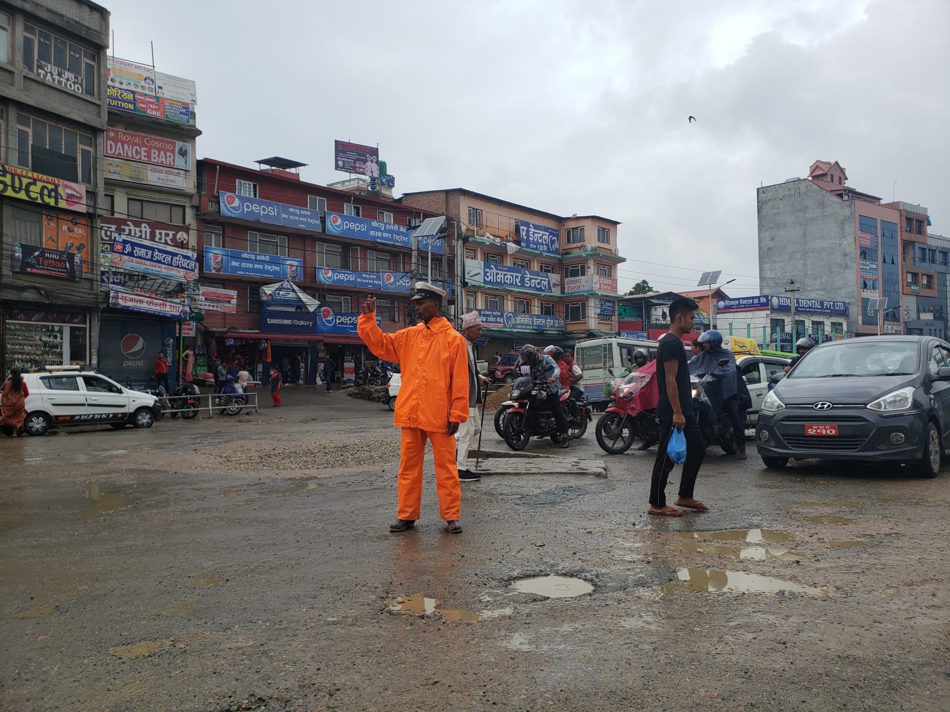 a man in an orange suit standing in a street with people and cars