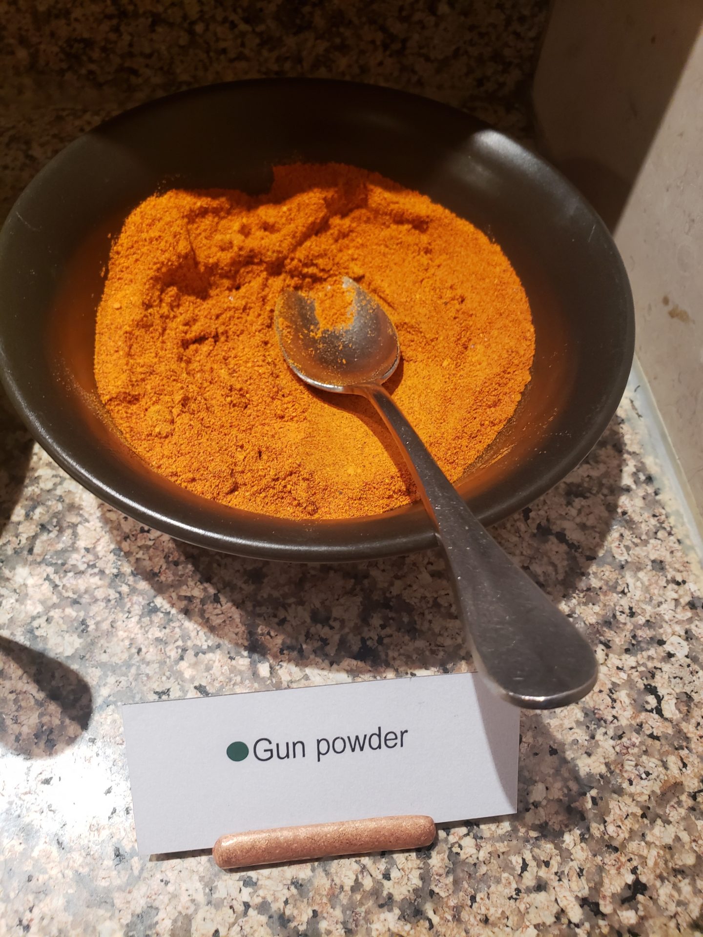 a bowl of powdered orange powder with a spoon