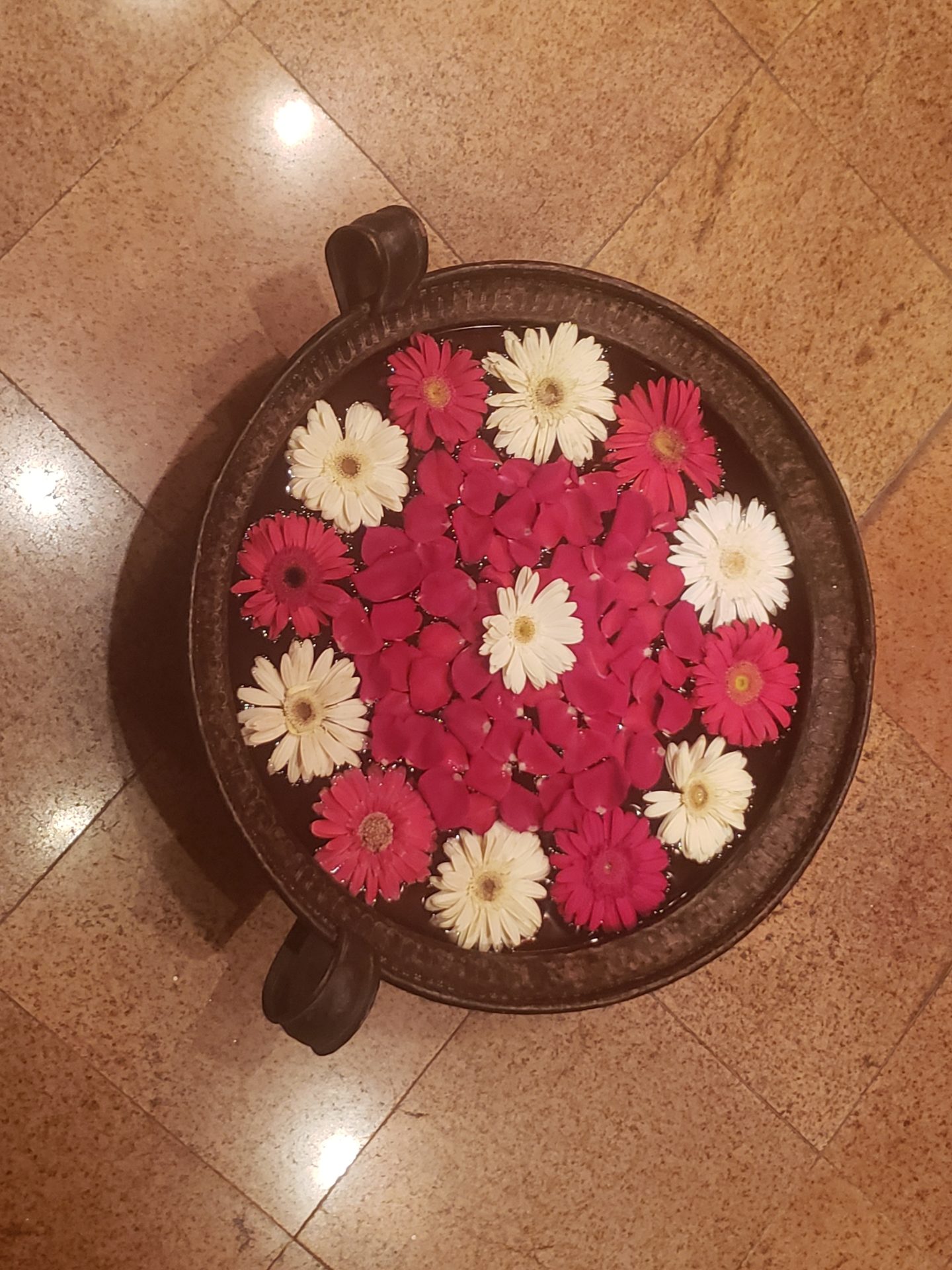a bowl of flowers on a tile floor