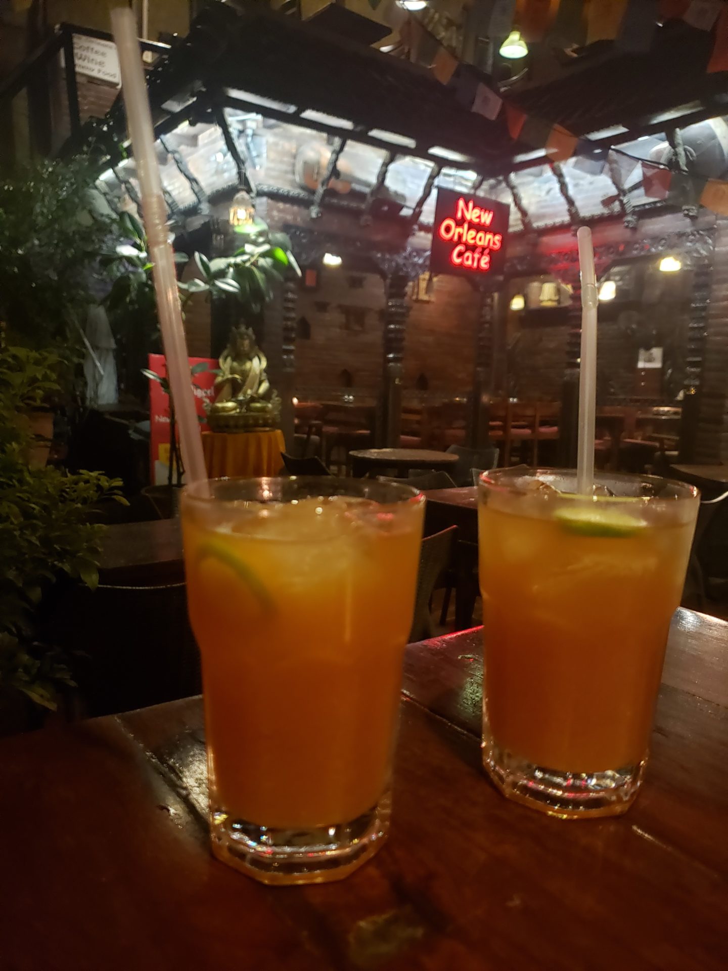 two glasses of orange liquid with straws on a table