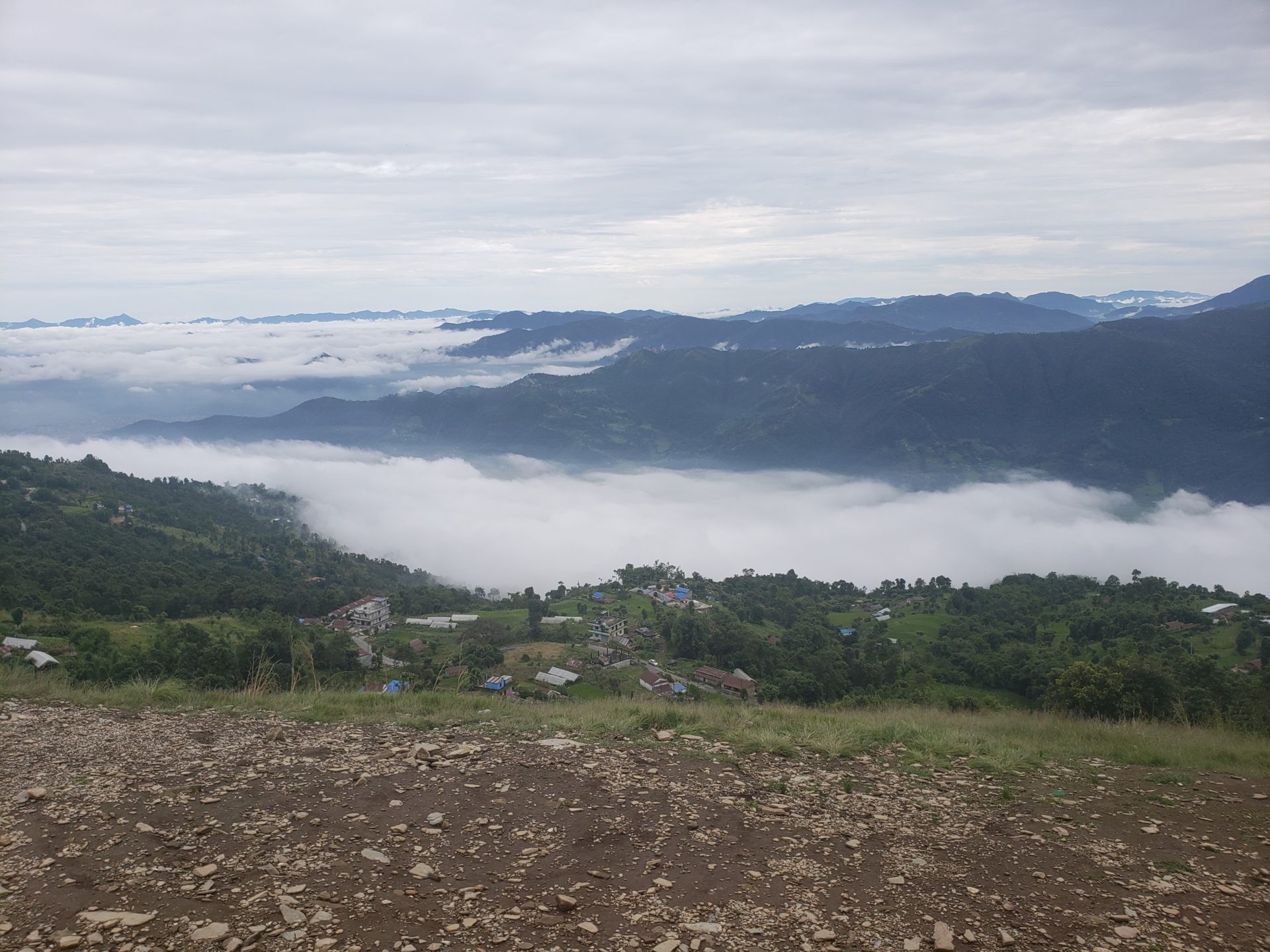 a landscape of a valley with clouds and a city