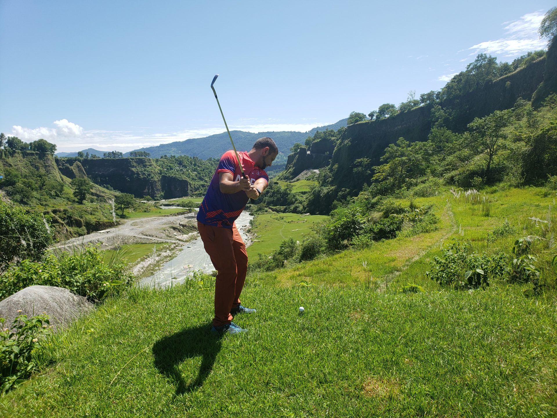 a man playing golf on a grassy hill
