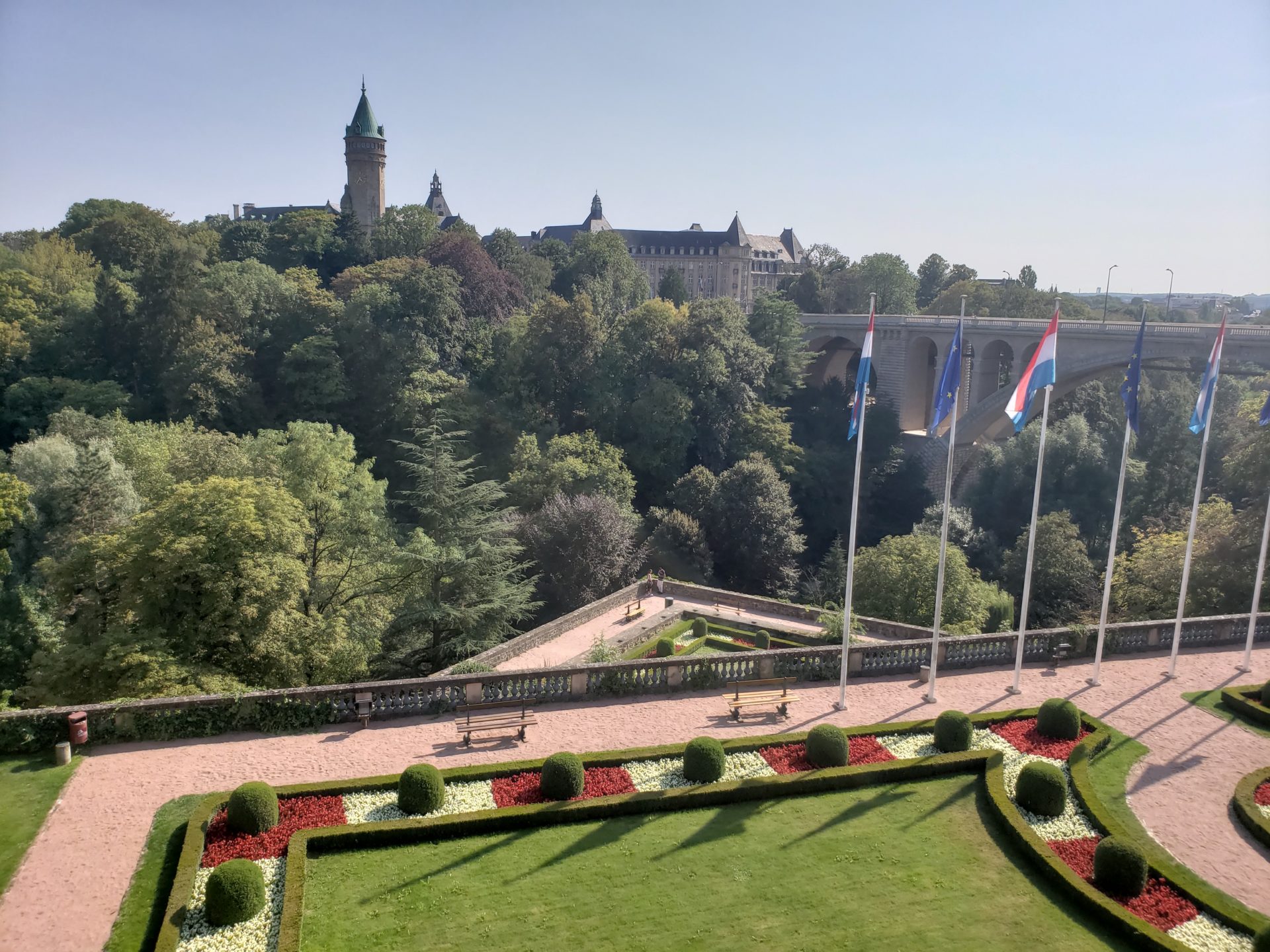 a park with flags and a bridge in the background