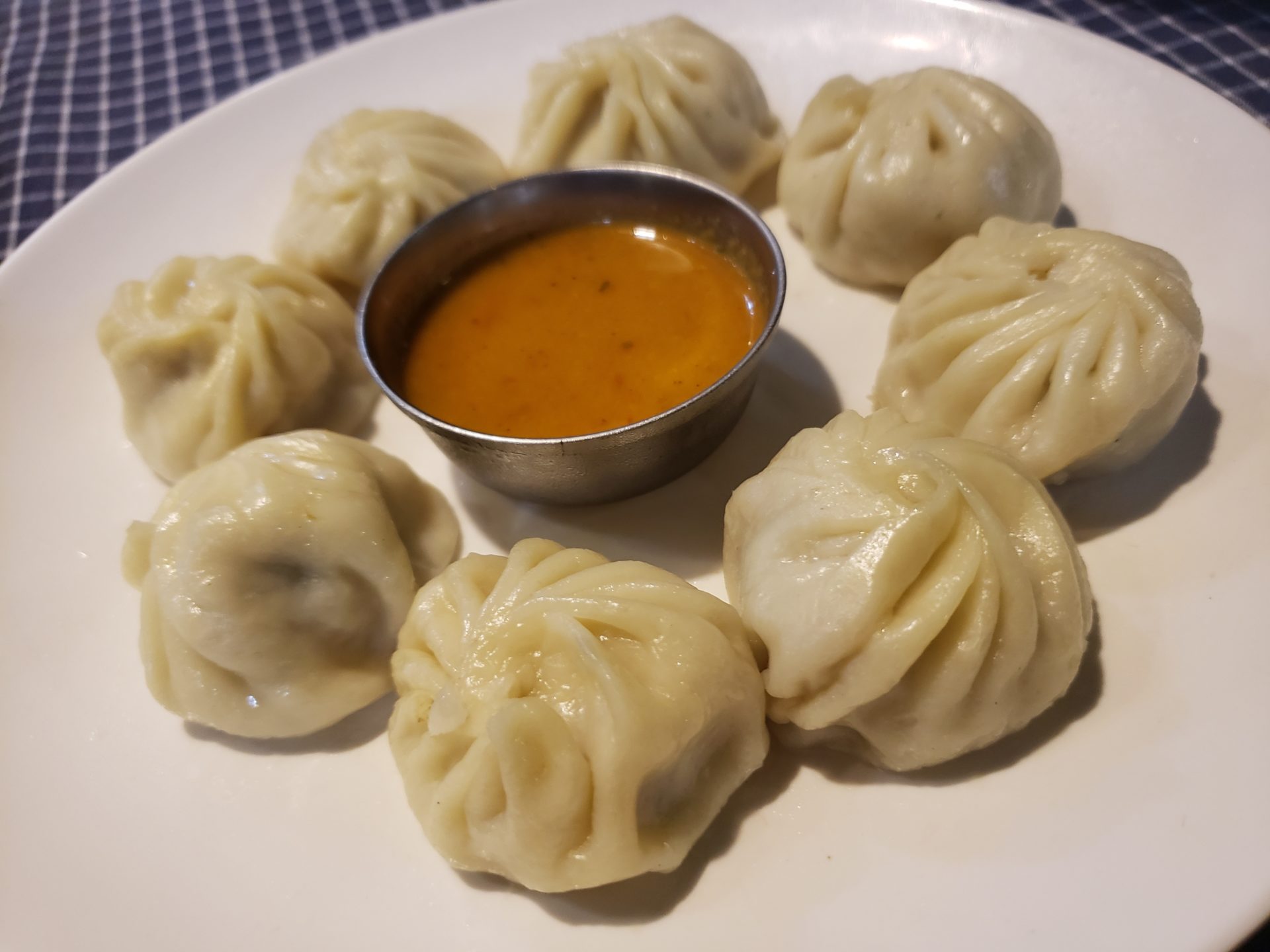 a plate of dumplings with a small cup of sauce