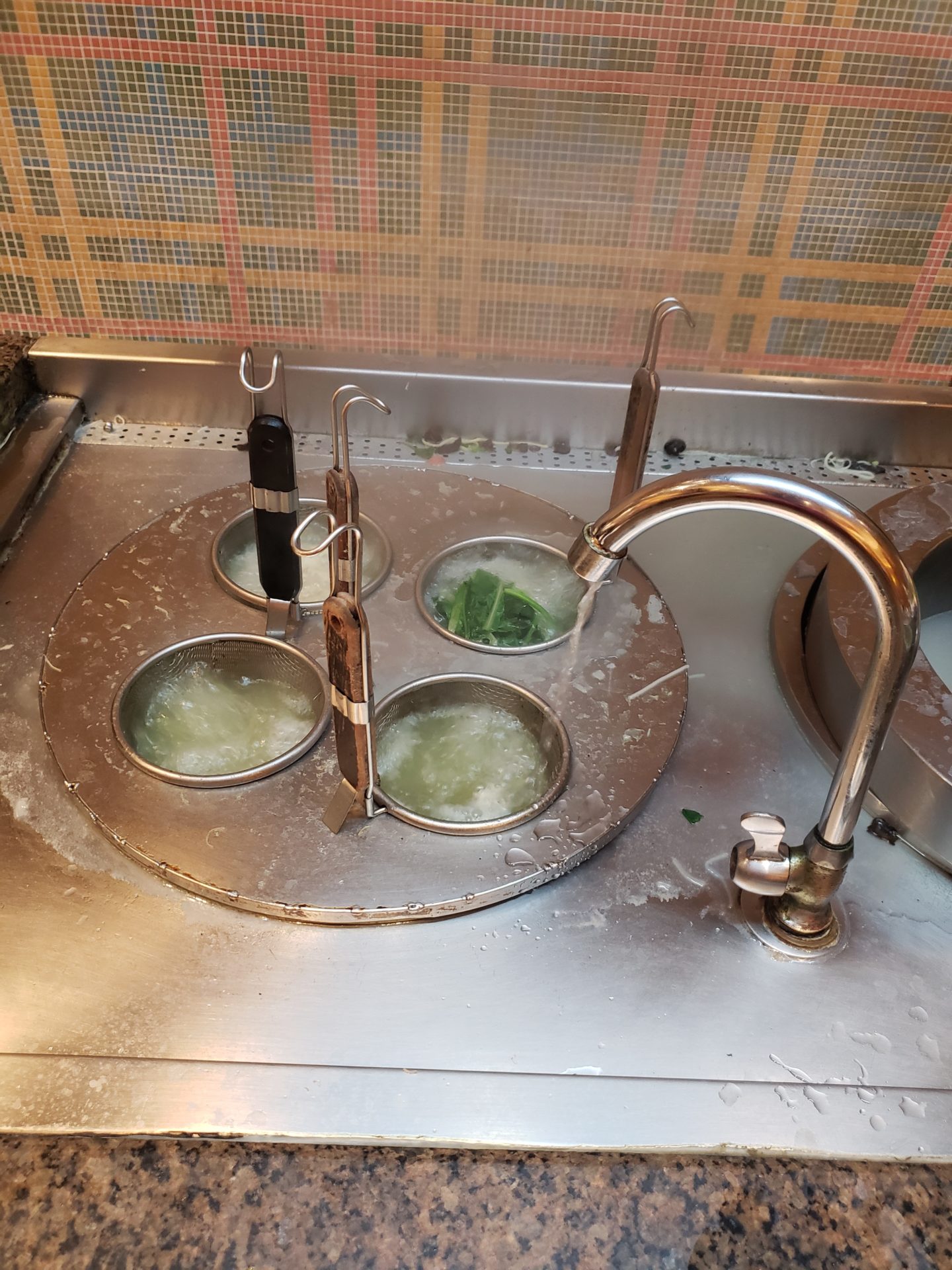 a sink with a faucet running water and utensils