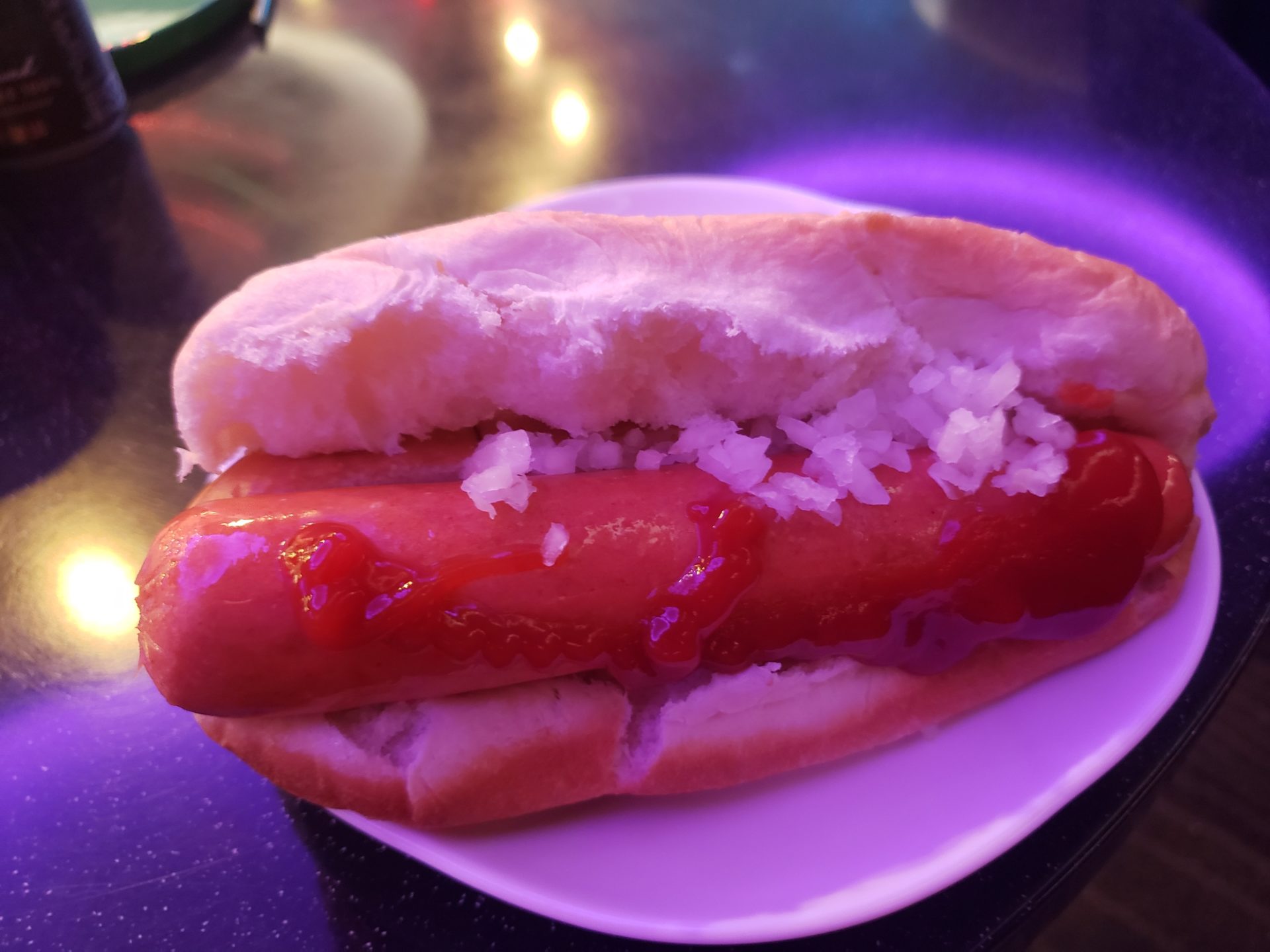 a hot dog with ketchup and rice on a plate