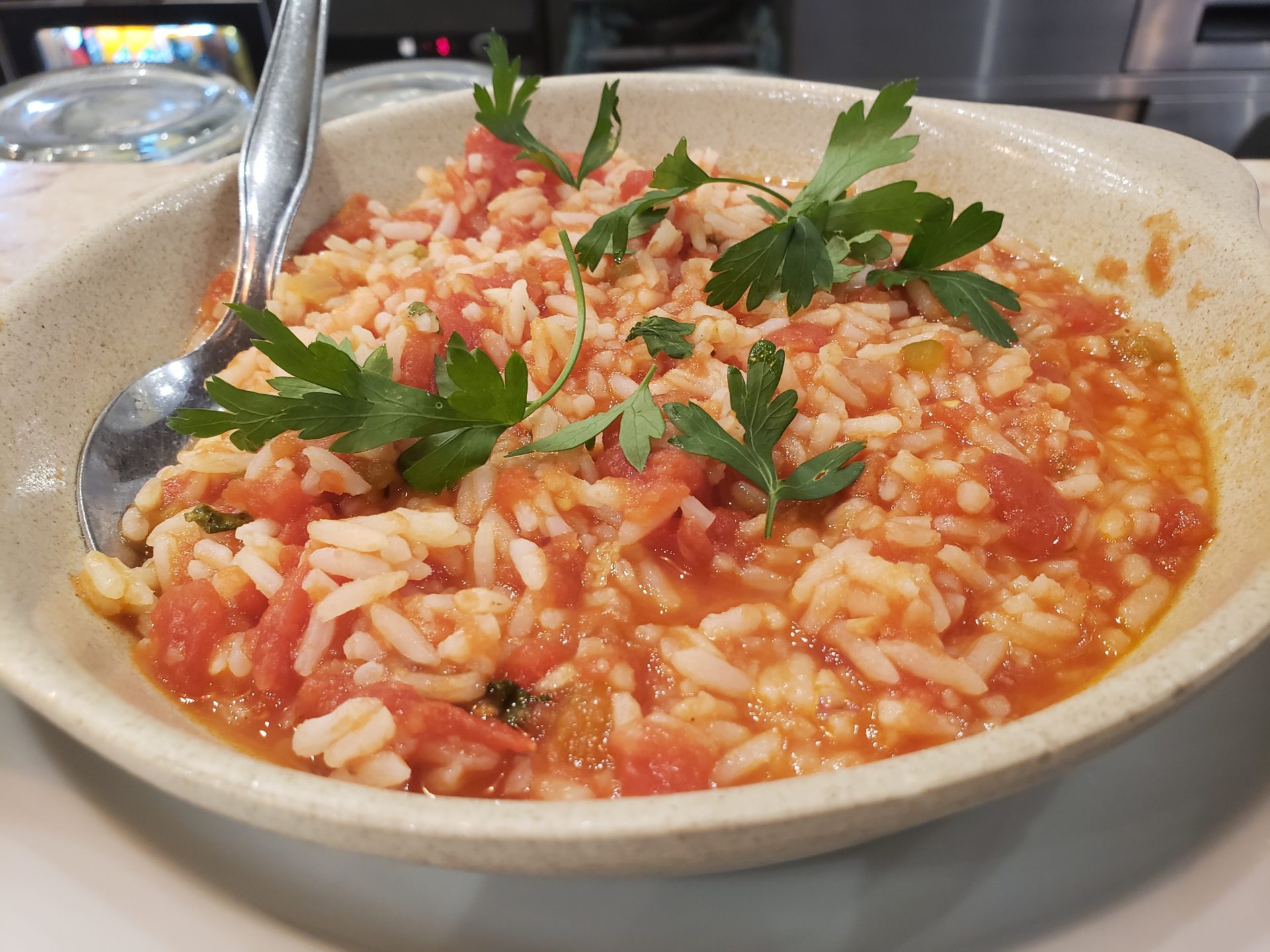 a bowl of rice and tomato sauce with a spoon