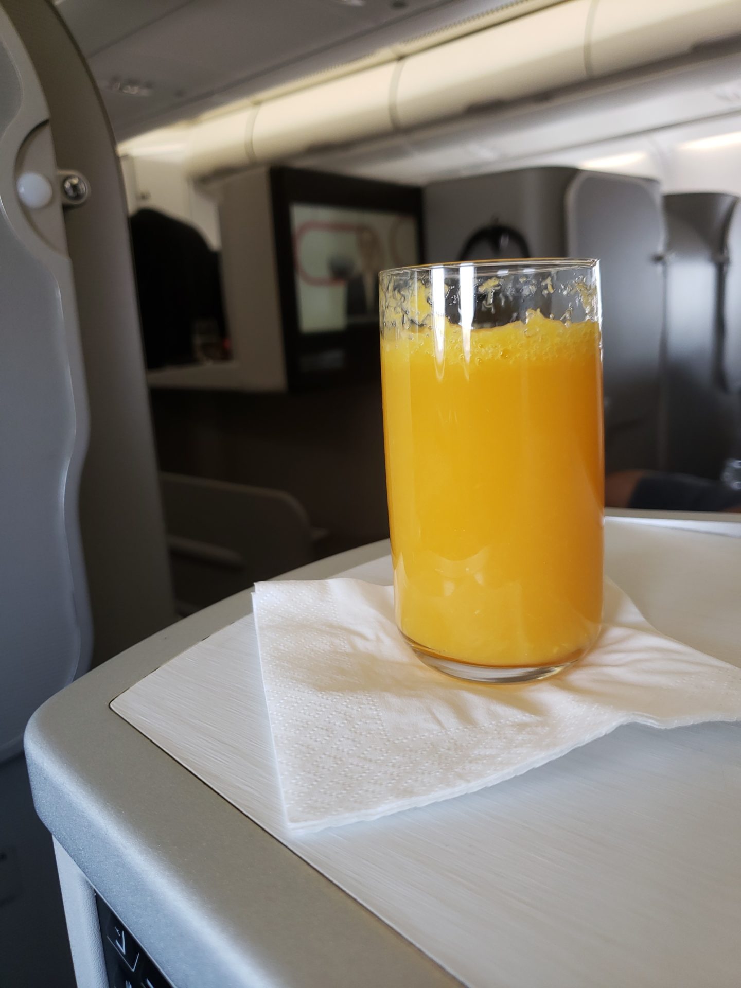 a glass of orange juice on a napkin on a table