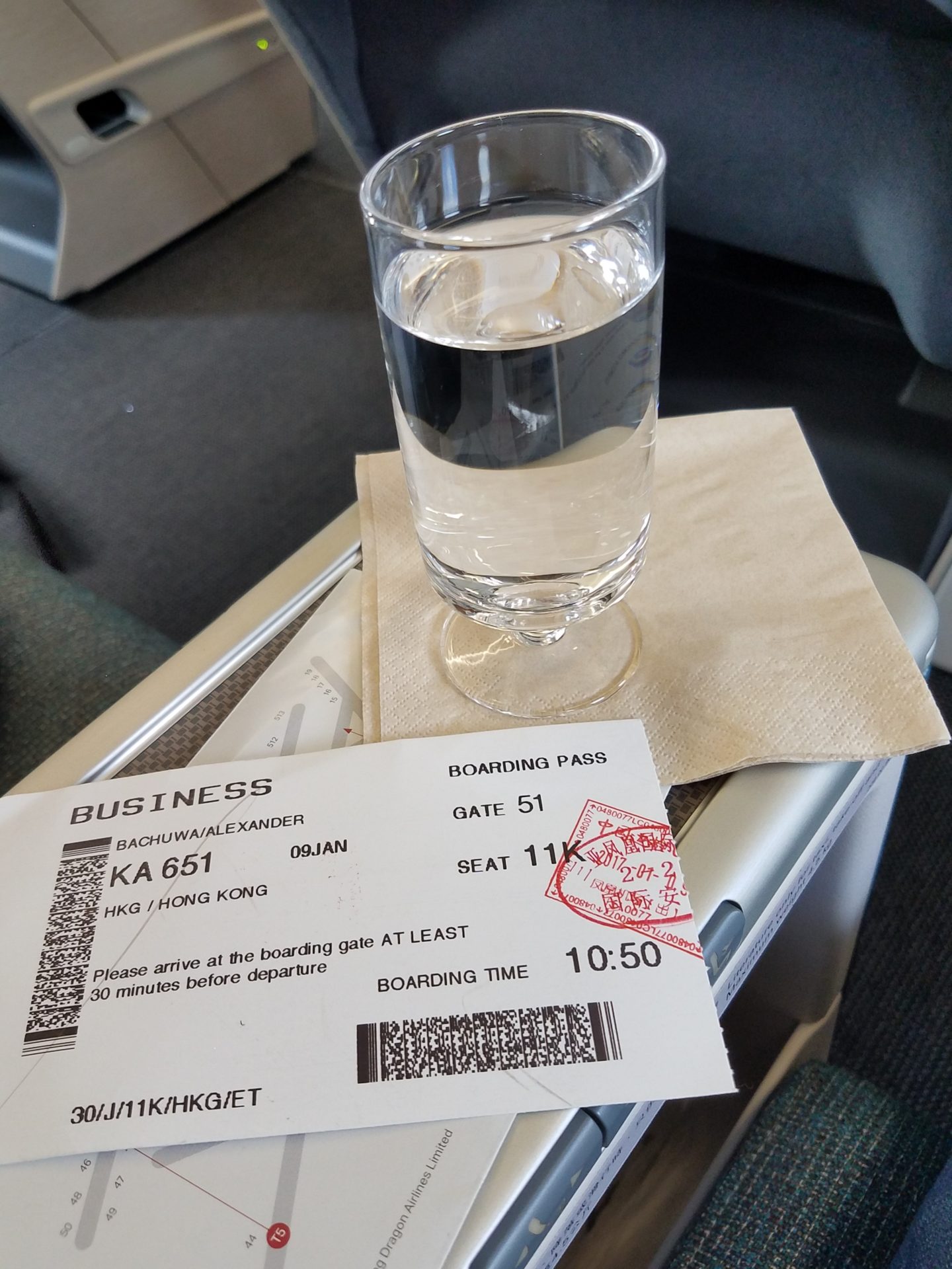 a glass of water on a napkin with a ticket on a plane