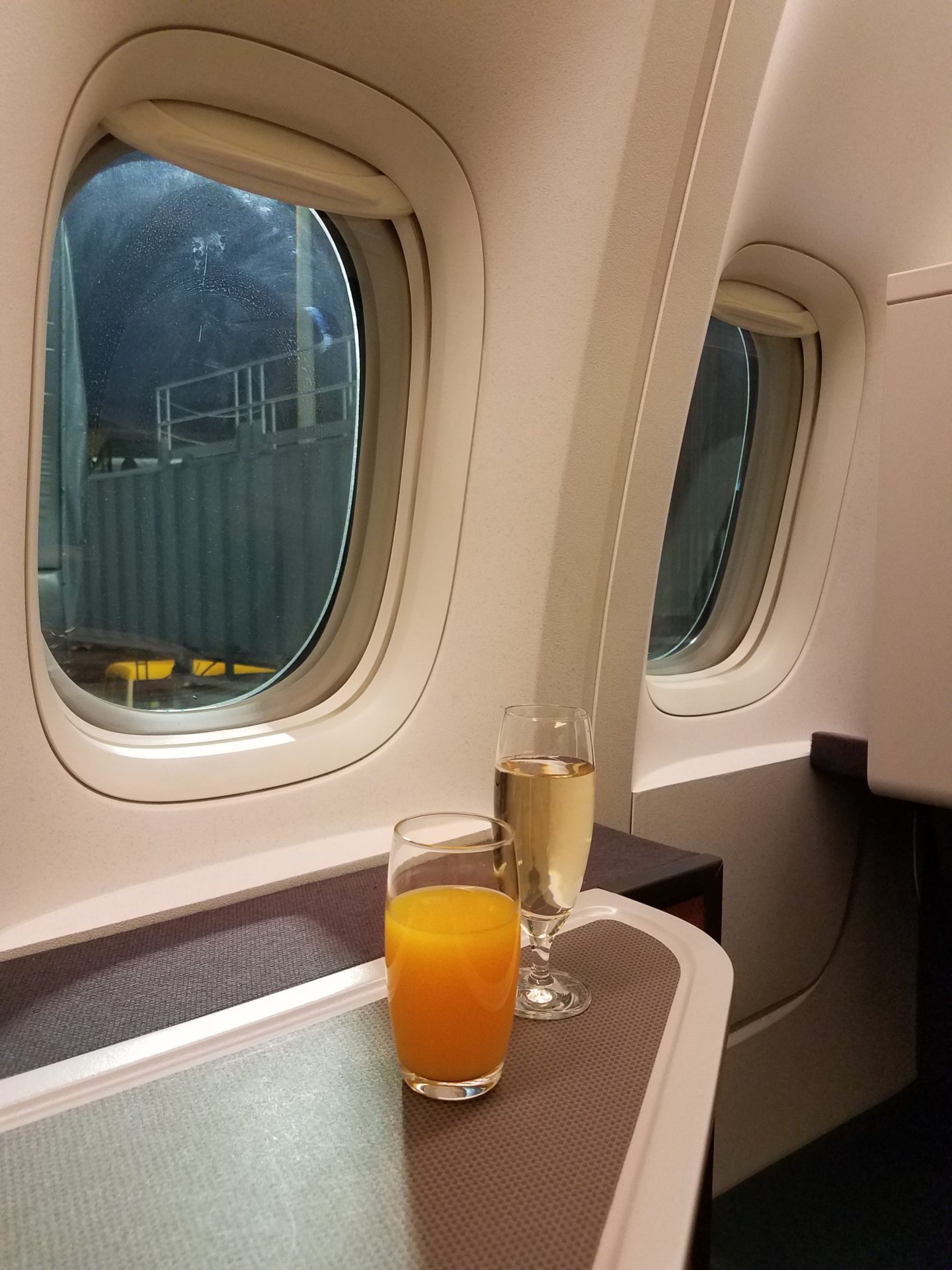 two glasses of juice and a glass of orange juice on a table in a plane