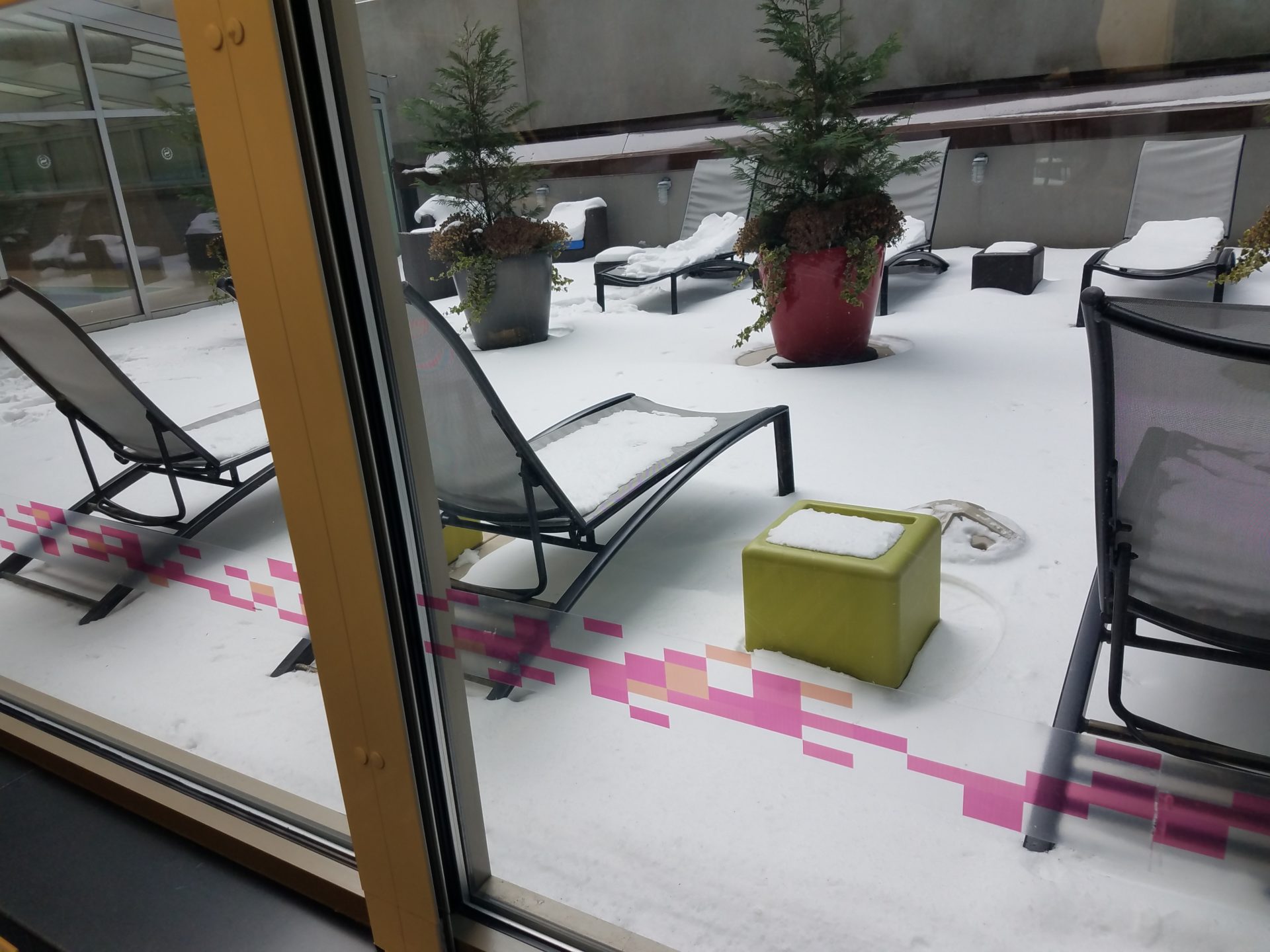 a snow covered patio area with chairs and plants