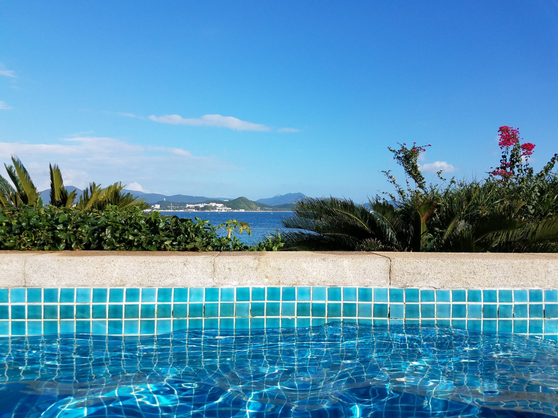 a pool with a view of the ocean and mountains in the background