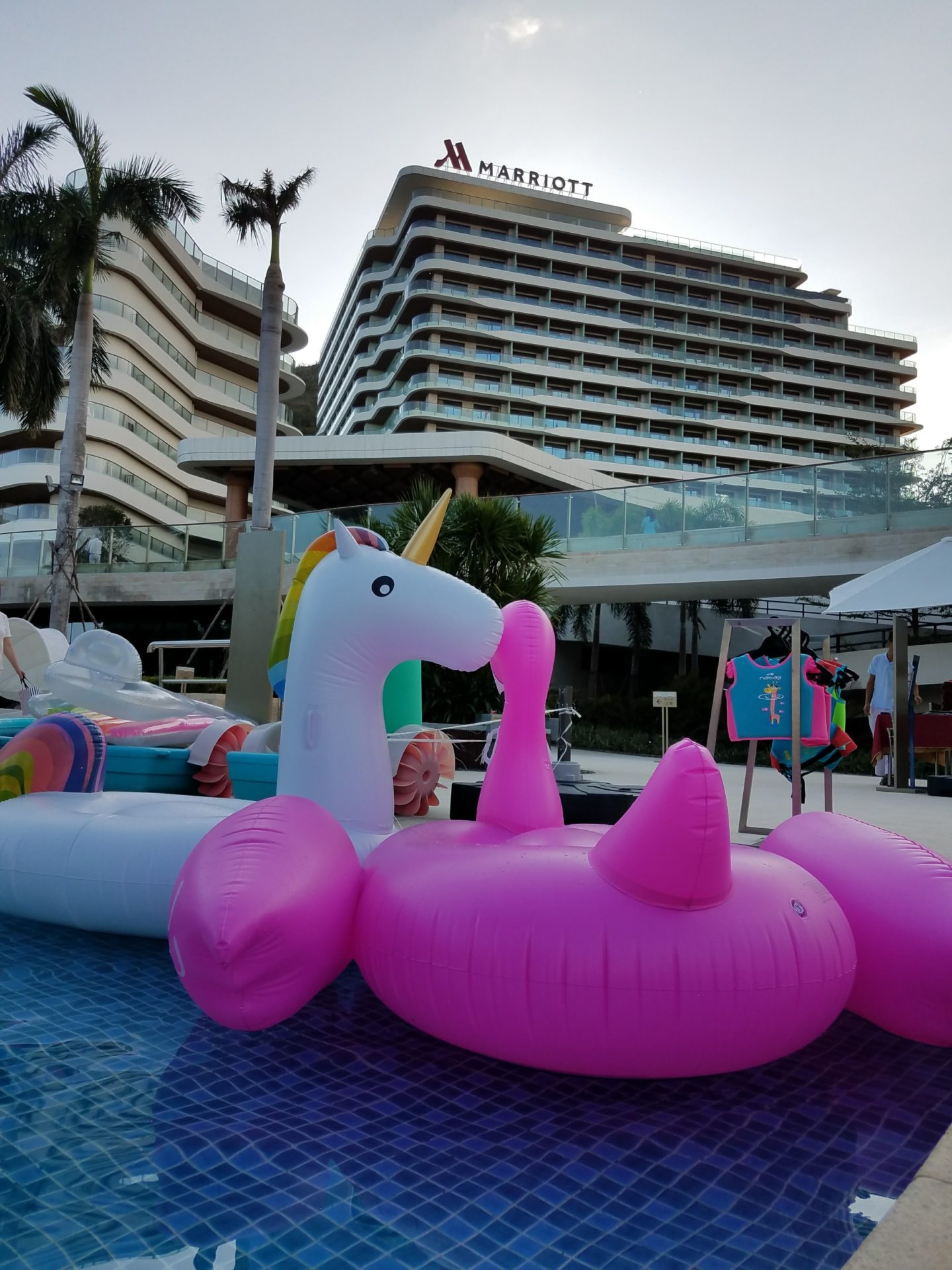 in a pool with inflatable toys in front of a hotel