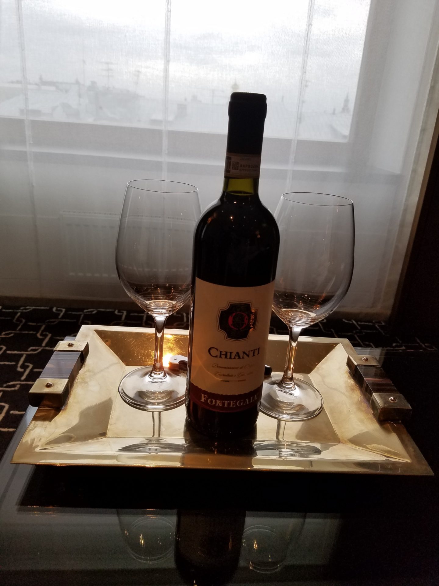 a bottle of wine and two wine glasses on a tray
