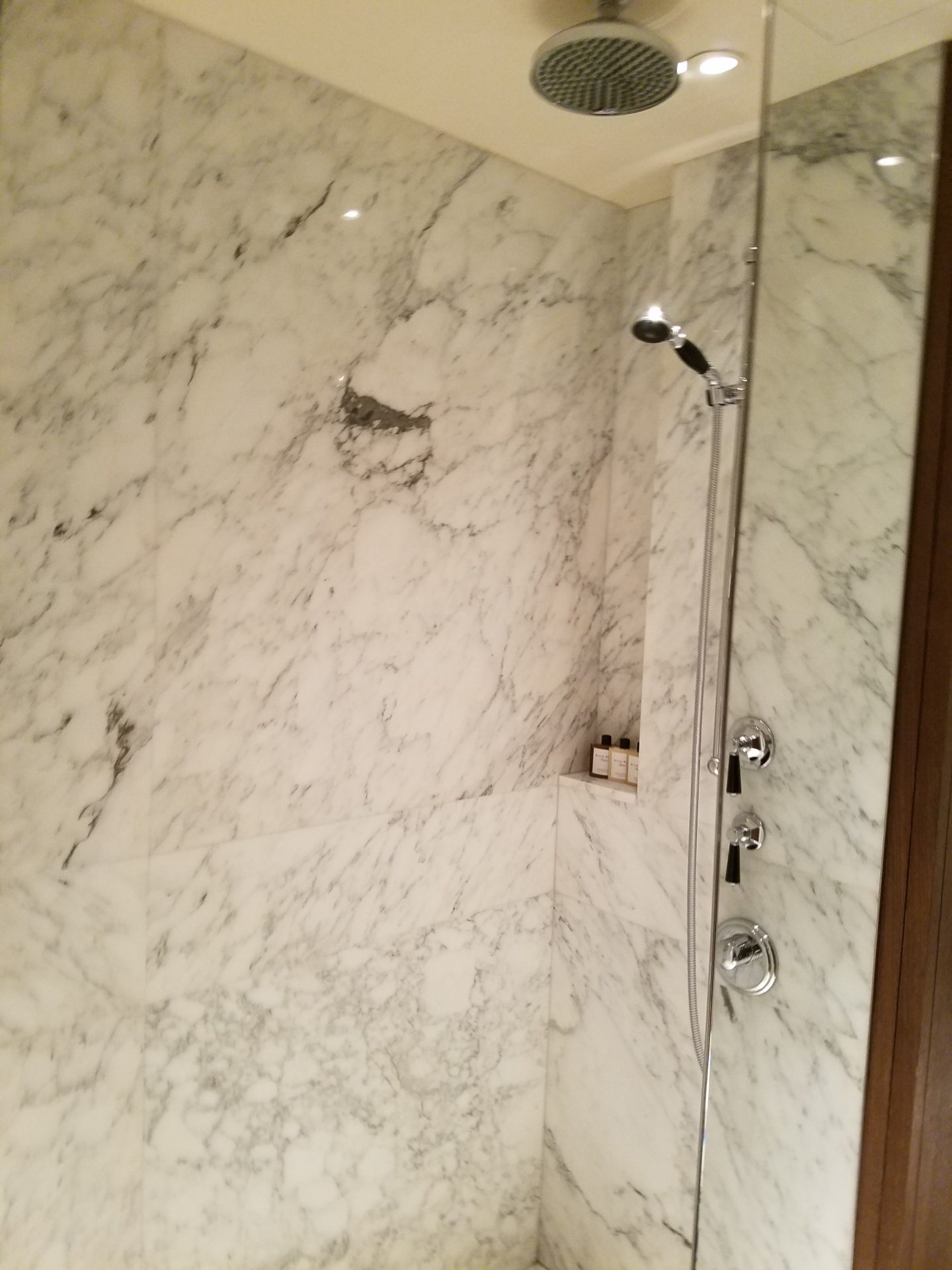 a shower with a marble wall